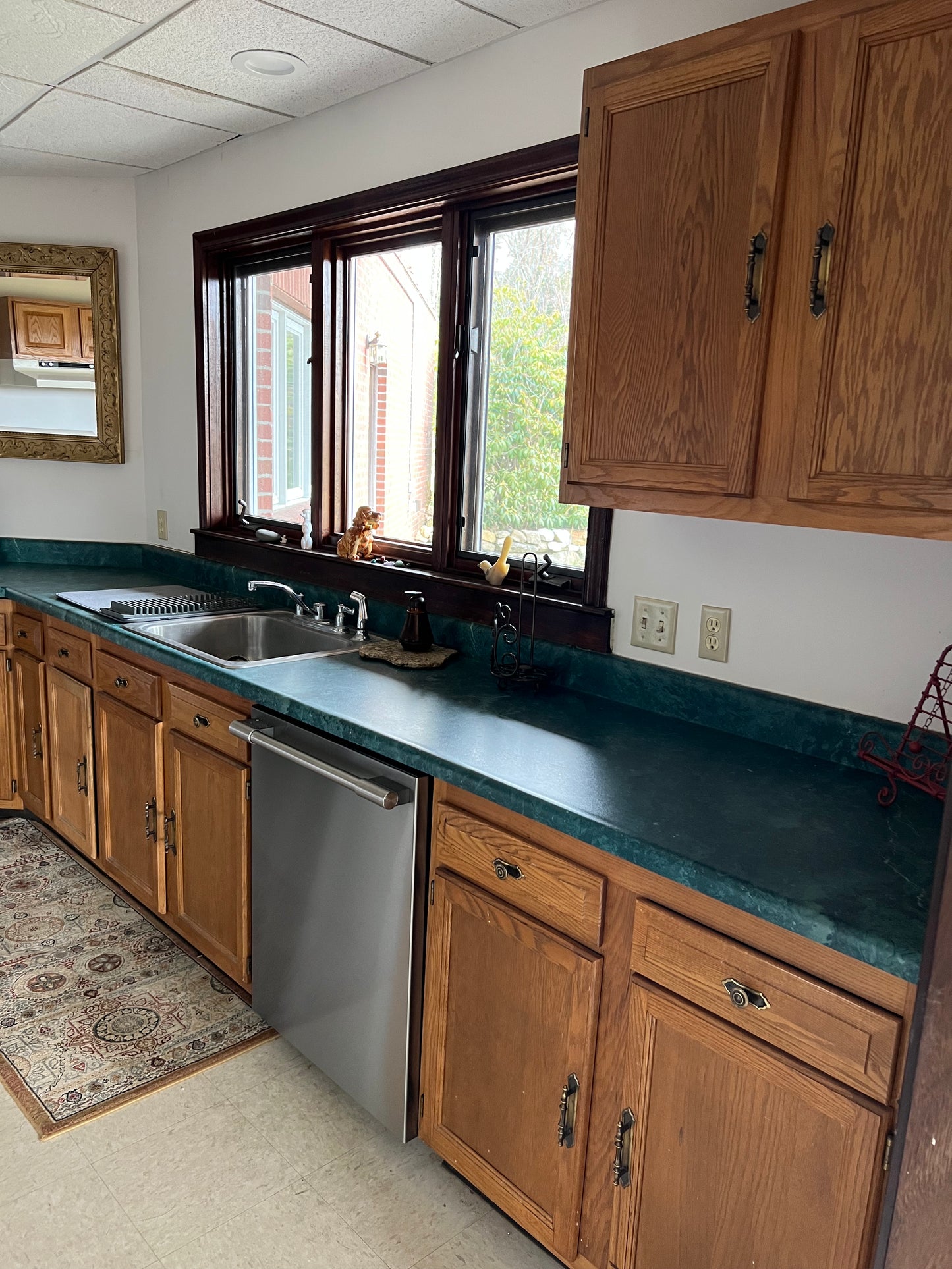 Kitchen with wooden cabinets, green countertops, and a window.
