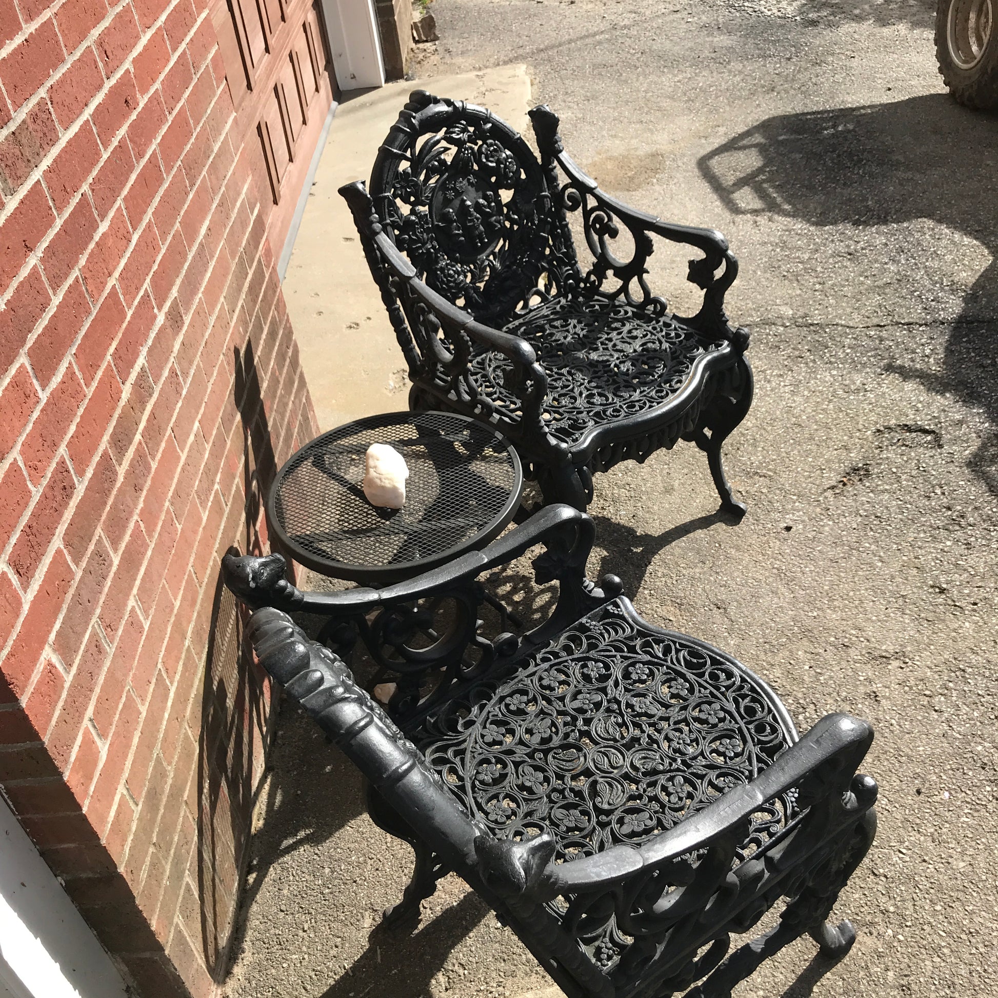 Decorative metal bench with intricate designs on a concrete wall.