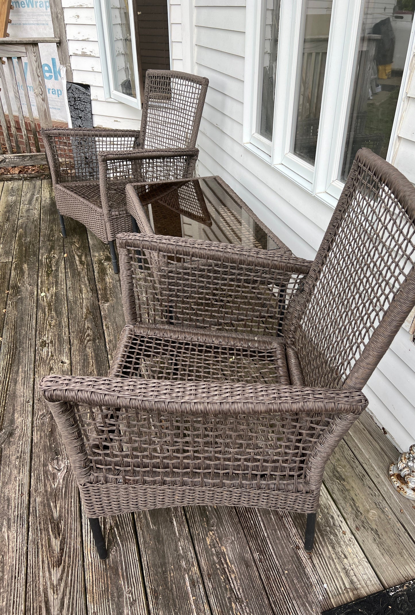 Wicker chairs on a wooden deck with a white building in the background