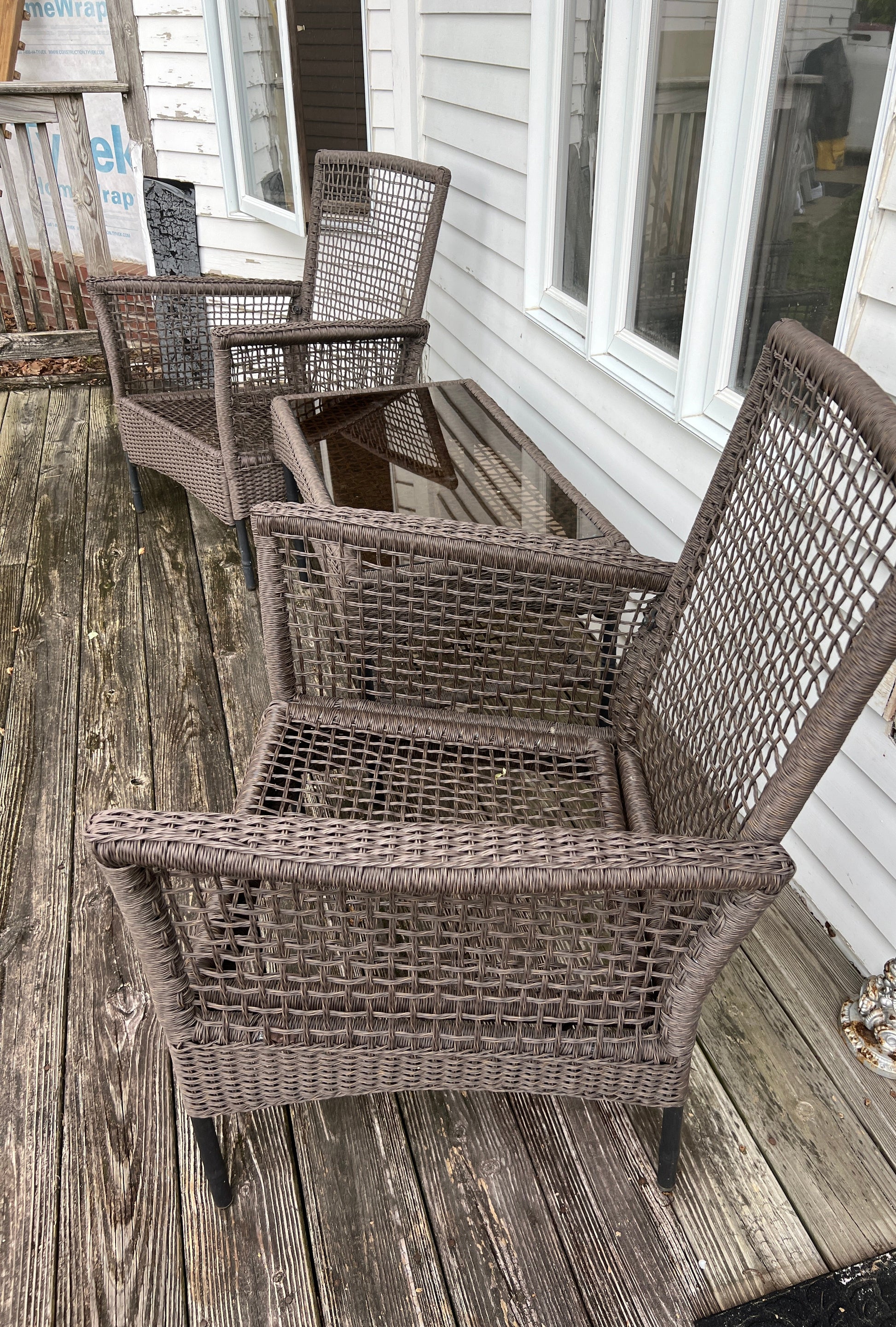 Wicker chairs on a wooden deck with a white building in the background