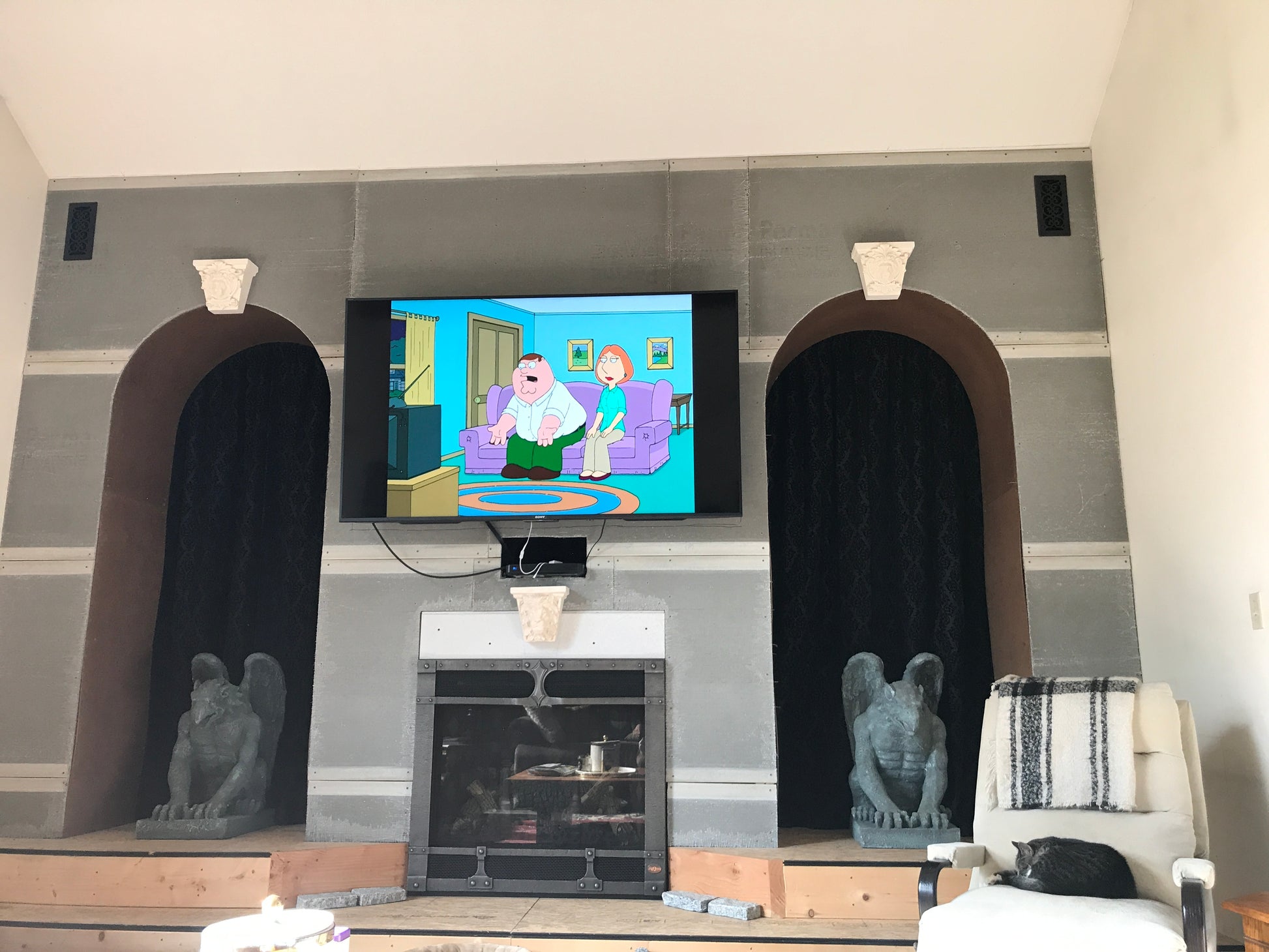 Living room with a TV displaying a cartoon, fireplace, and decorative arches.
