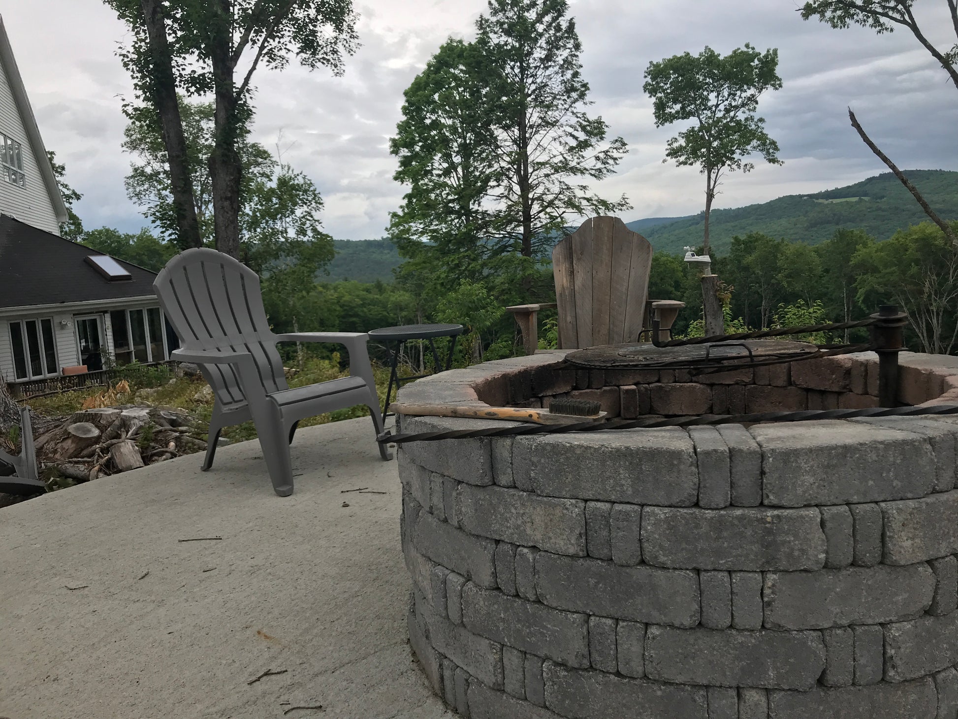 Patio with stone fire pit and Adirondack chairs overlooking a scenic view.