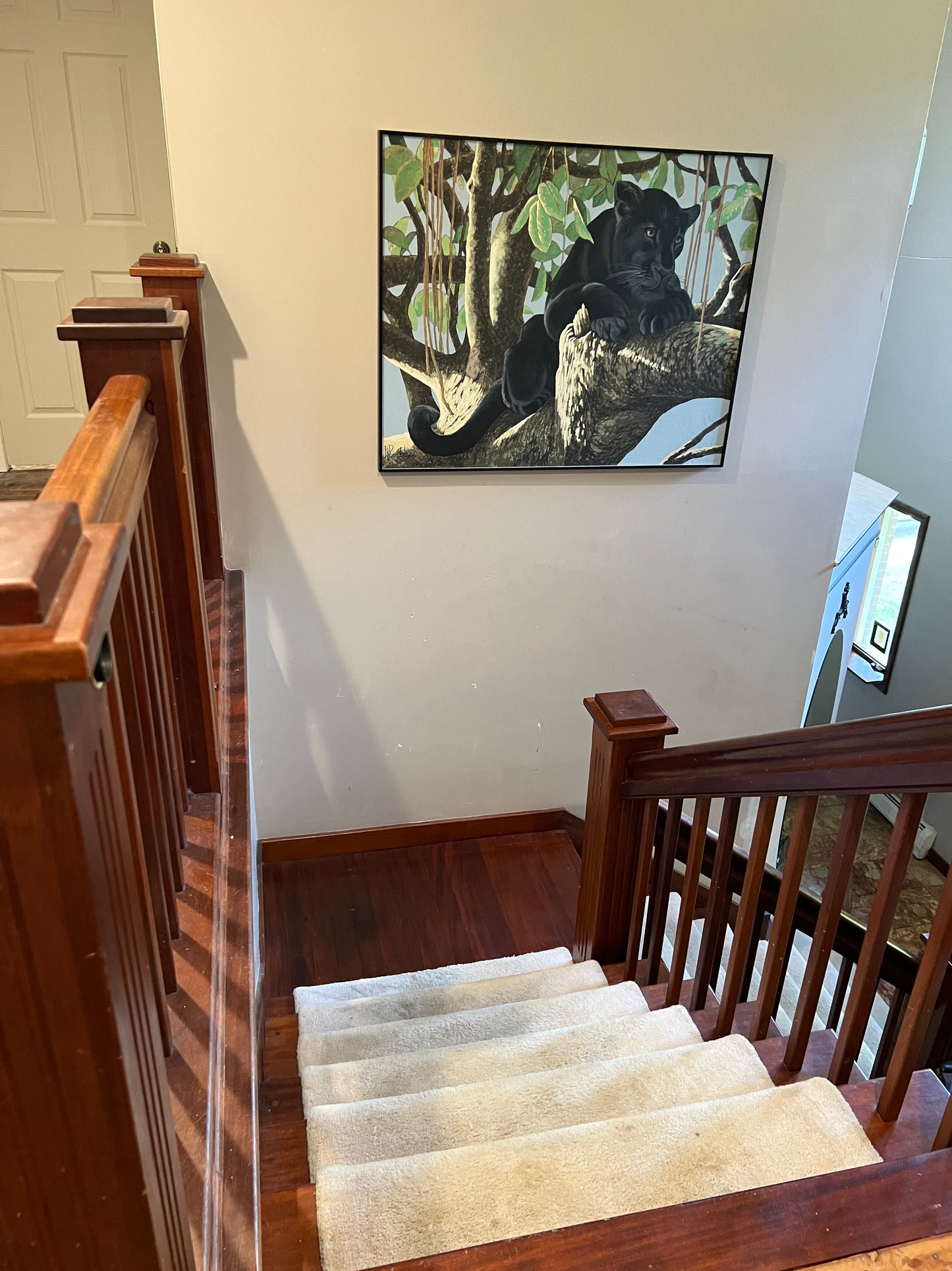 Wooden staircase with a painting of a black panther on the wall.