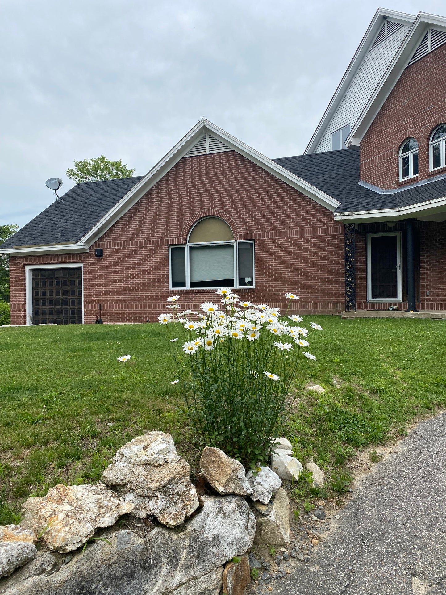 Brick house with  wildflowers and a grassy area and stone wall