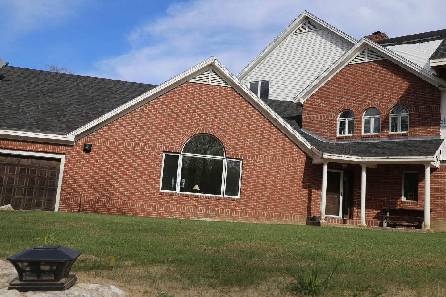 Brick house with a gray roof and white trim on a clear day