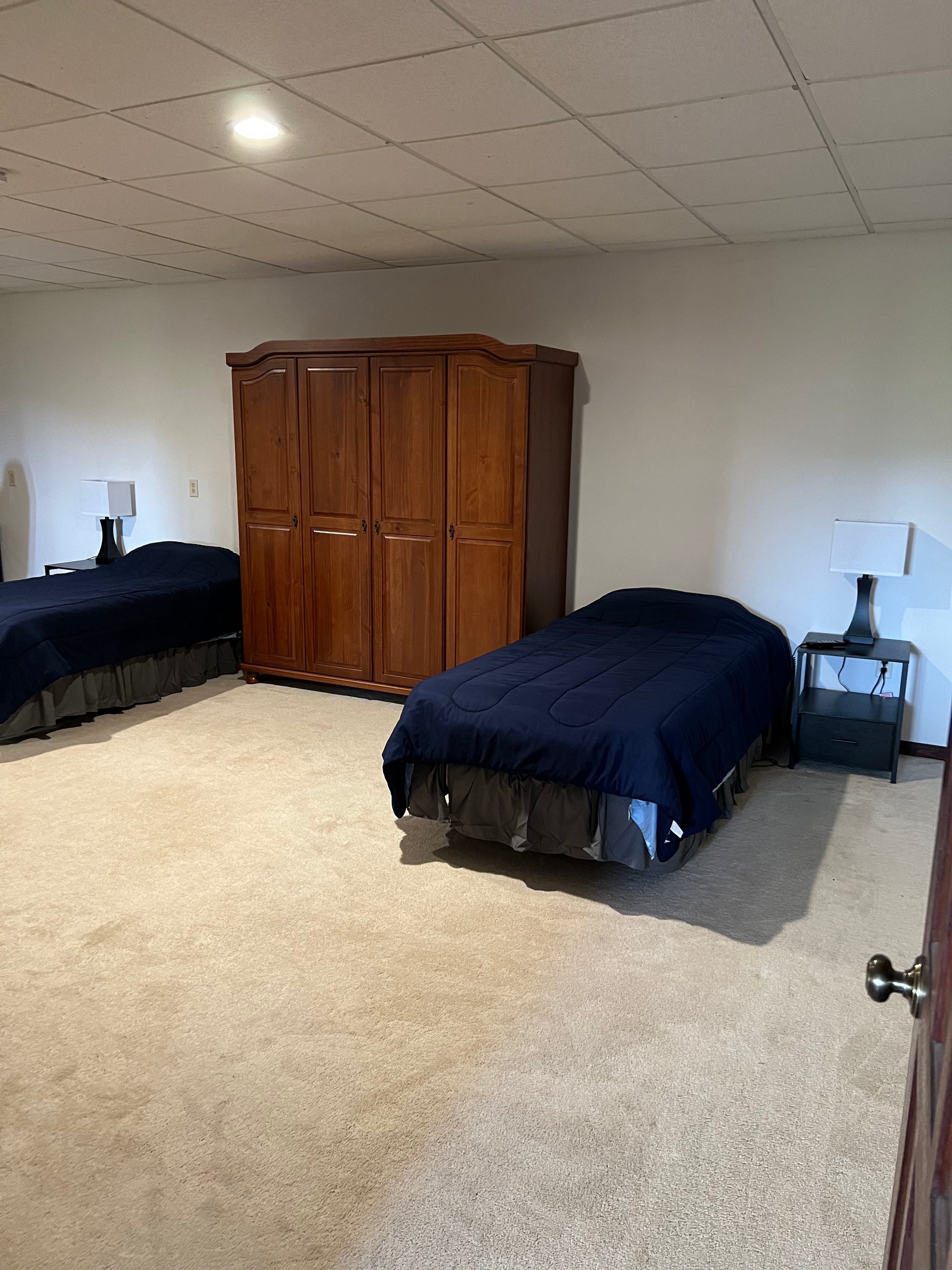 Bedroom with two beds and a wooden wardrobe.