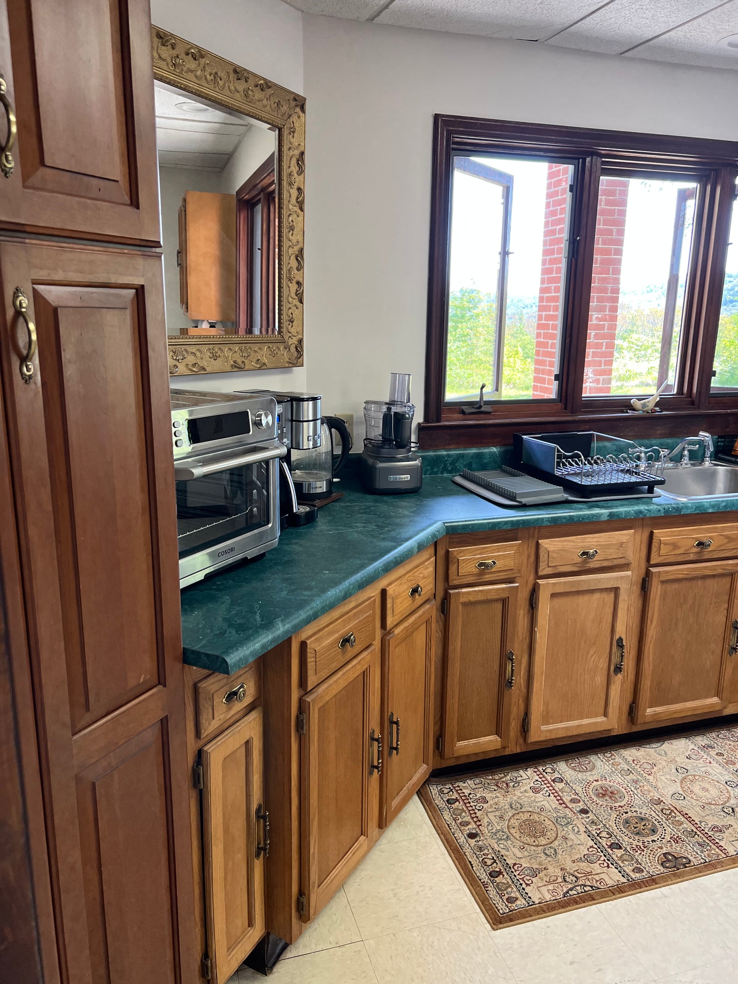 Kitchen with wooden cabinets, green countertop, and window view Nature View NH Estate