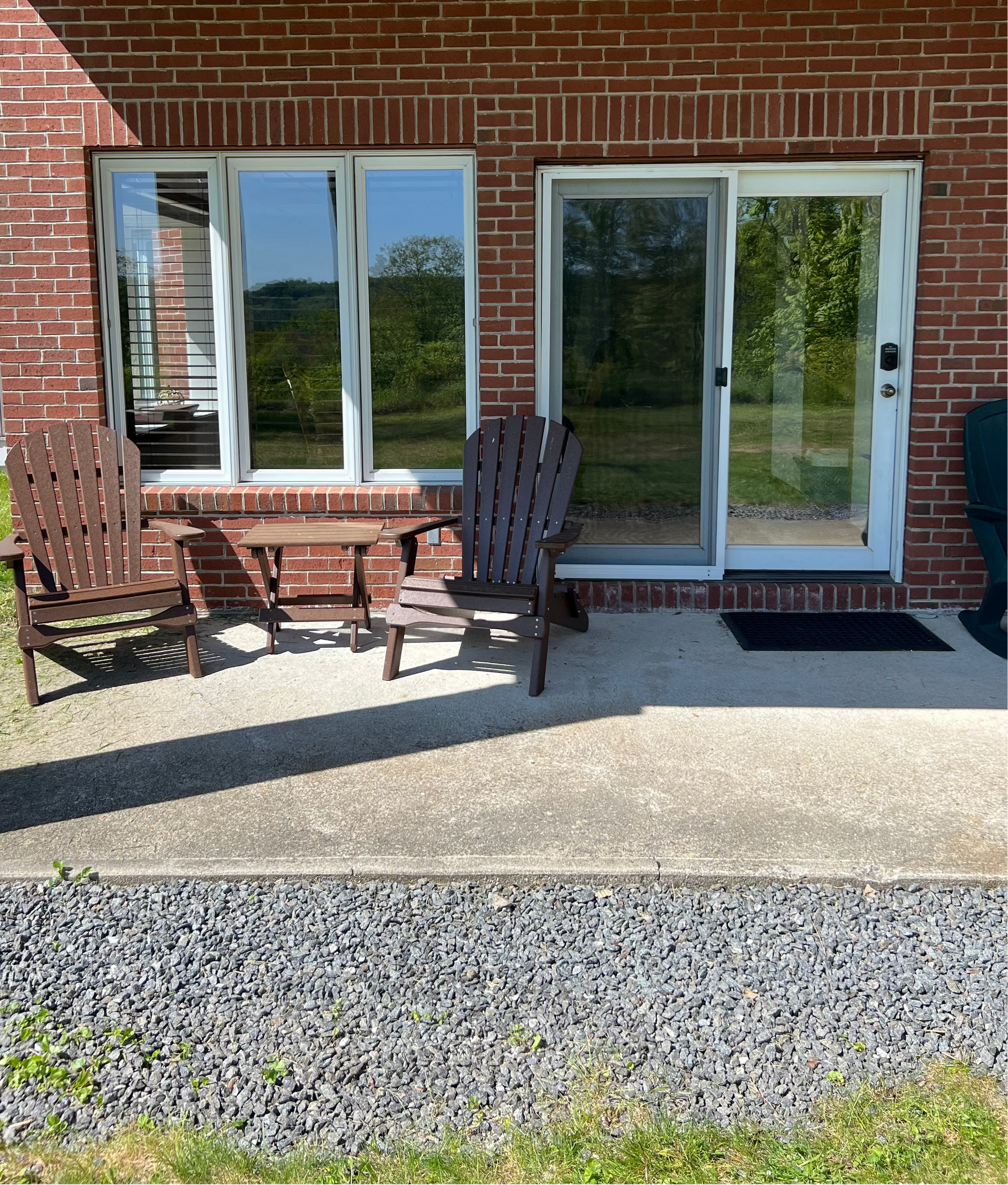 Outdoor patio area with chairs and a sliding glass door on a brick house.