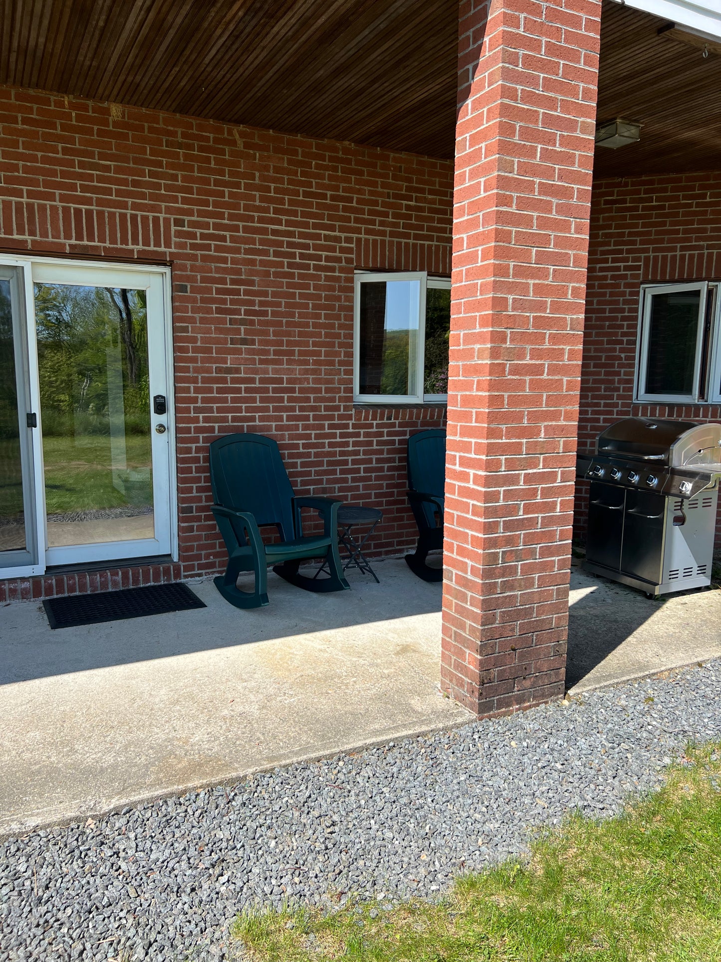 Outdoor patio area with a brick building, green chair, and grill.