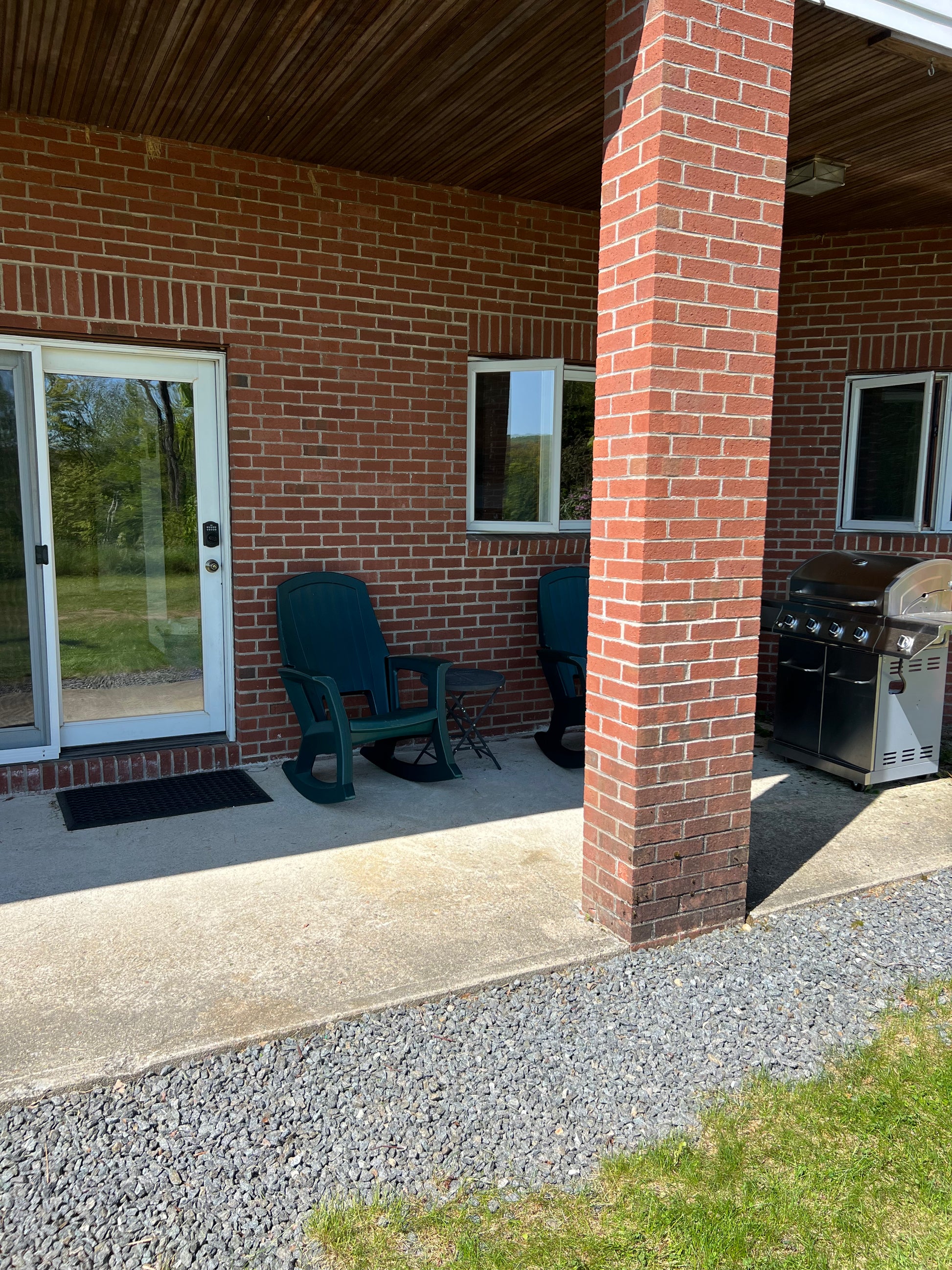 Outdoor patio area with a brick building, green chair, and grill.