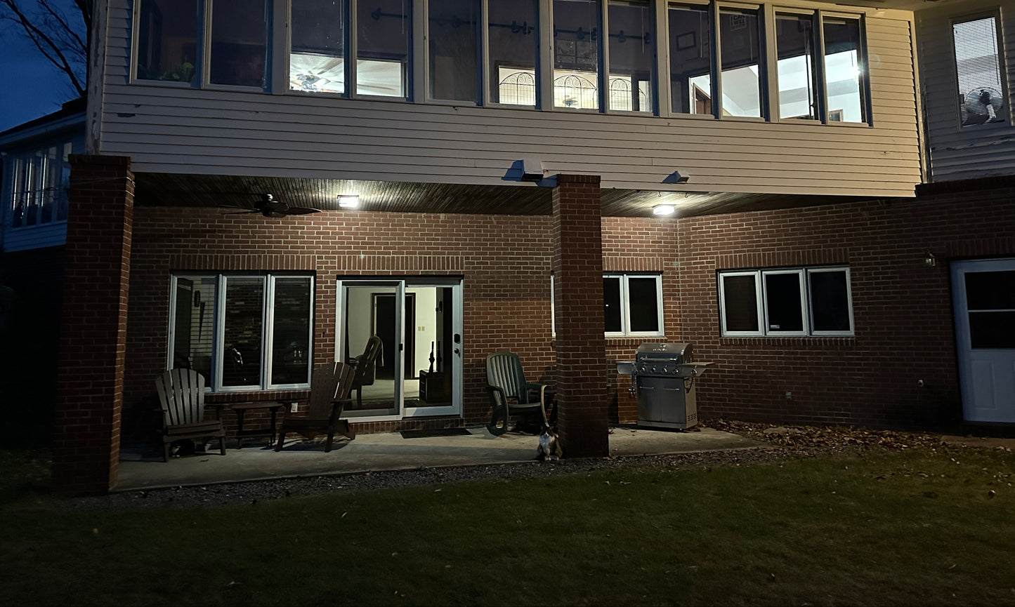  House with lit windows at night. With chairs on the late night patio.
