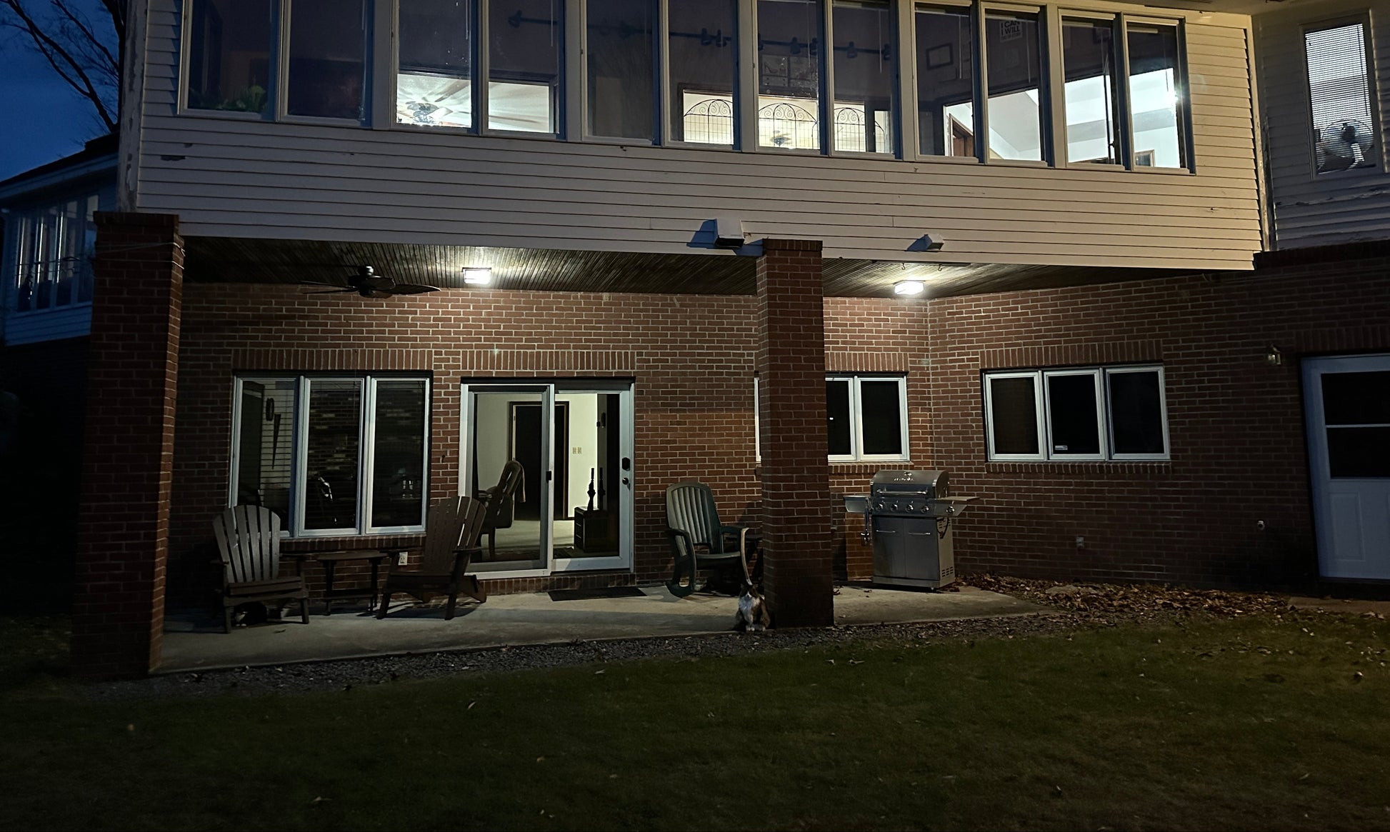  House with lit windows at night. With chairs on the late night patio.