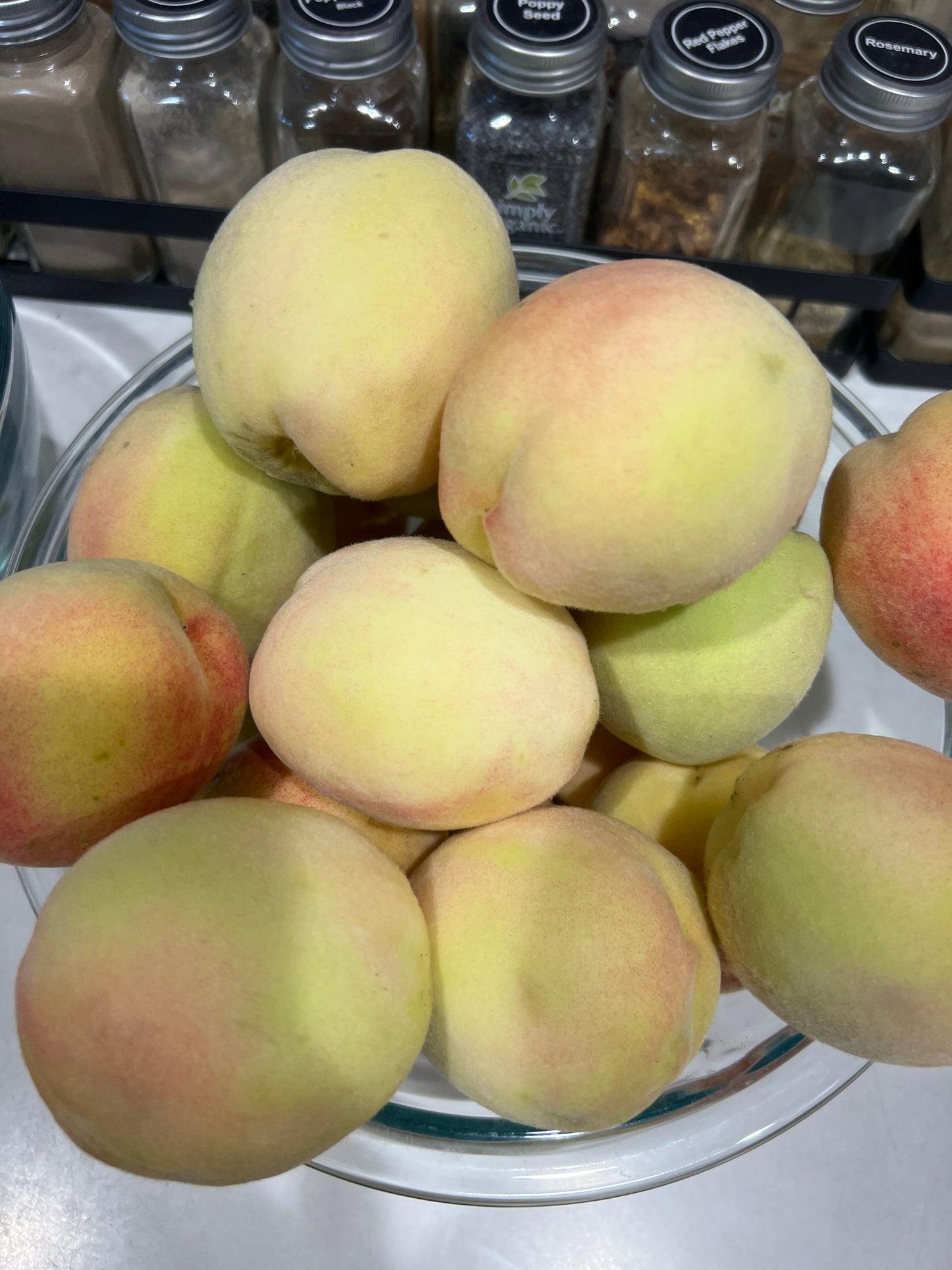 Glass bowl filled with peaches on a kitchen counter