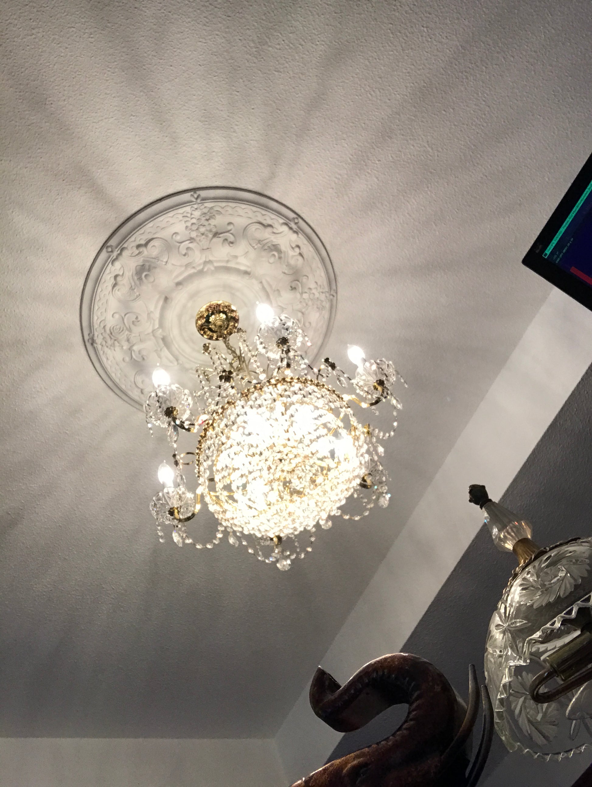 Decorative crystal chandelier  light fixture with intricate design on a white walls.