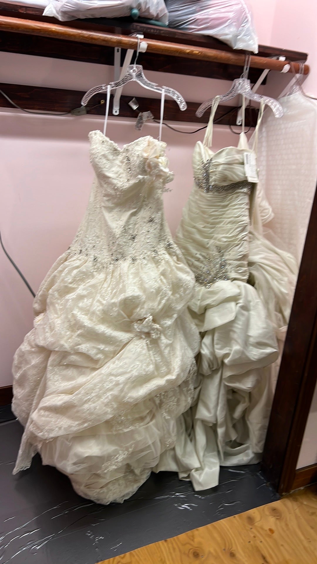 White lace wedding dress on a hanger with a pink background
