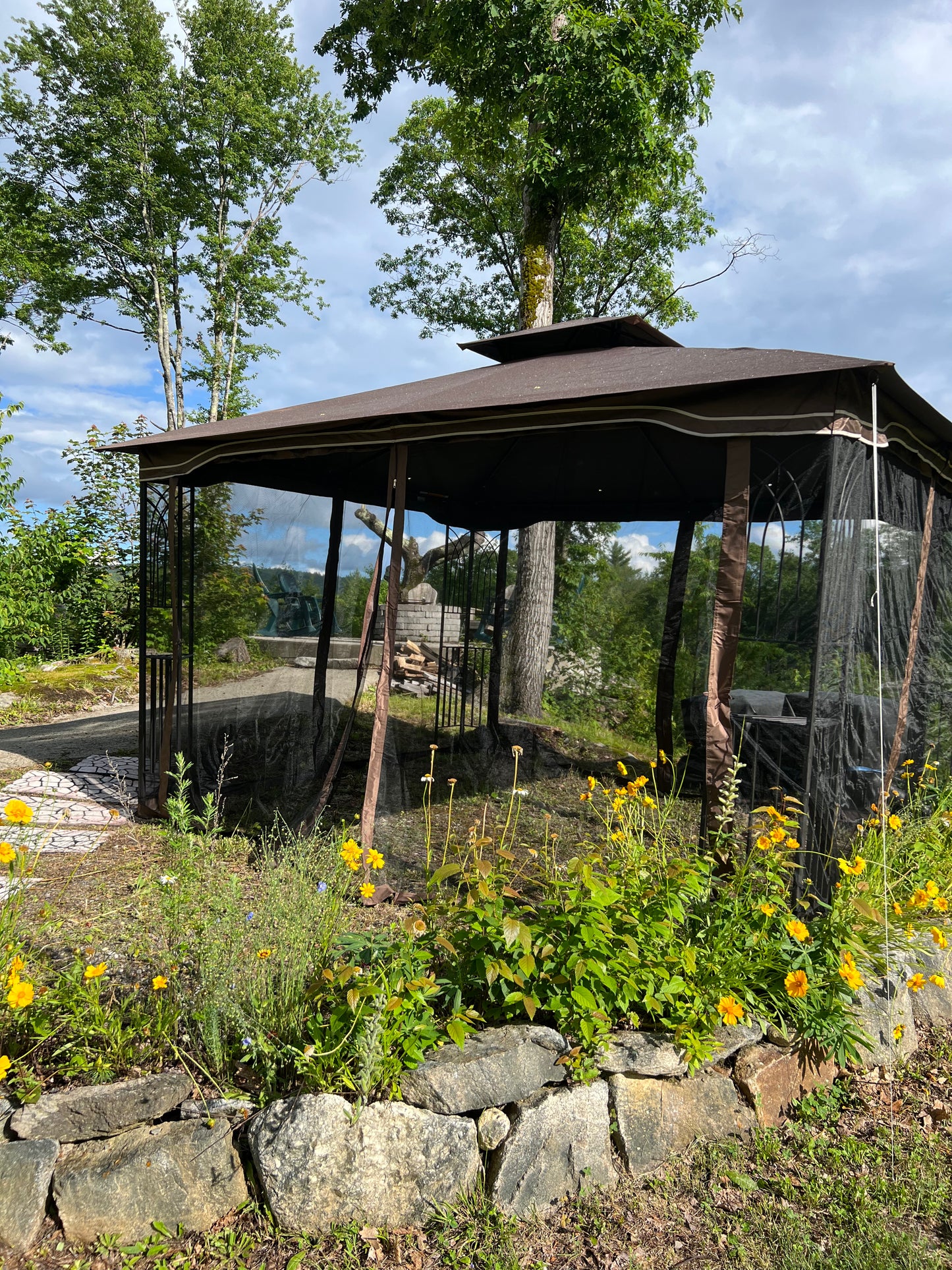 Gazebo with screen walls in a natural setting with trees and rocks.