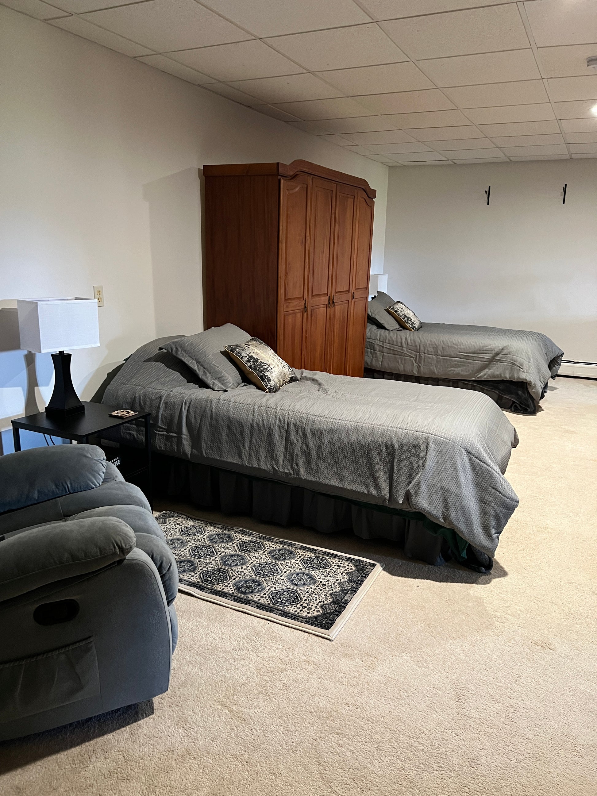 Gray massage chair in a room with tiled walls and a wooden cabinet.