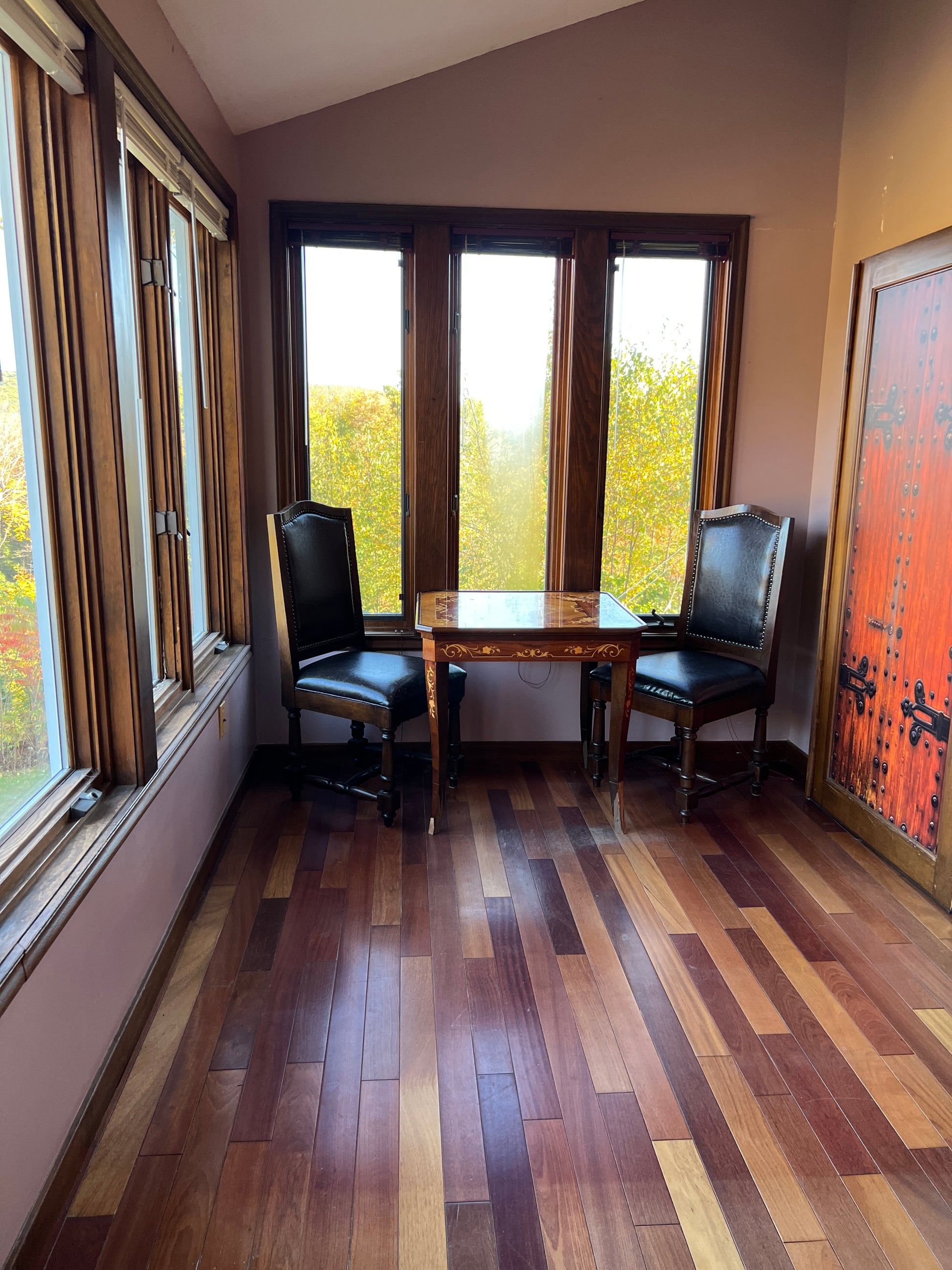 Sunroom with chair in a room with wooden floor  and large windows.