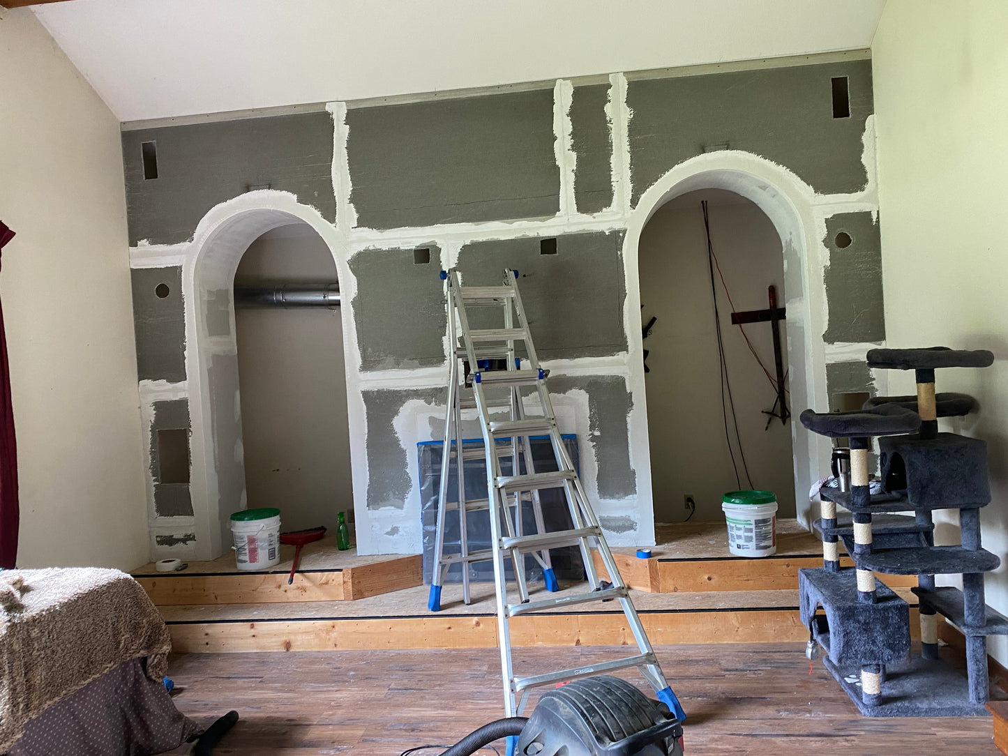 Room under construction with gray walls, arches, and a ladder.