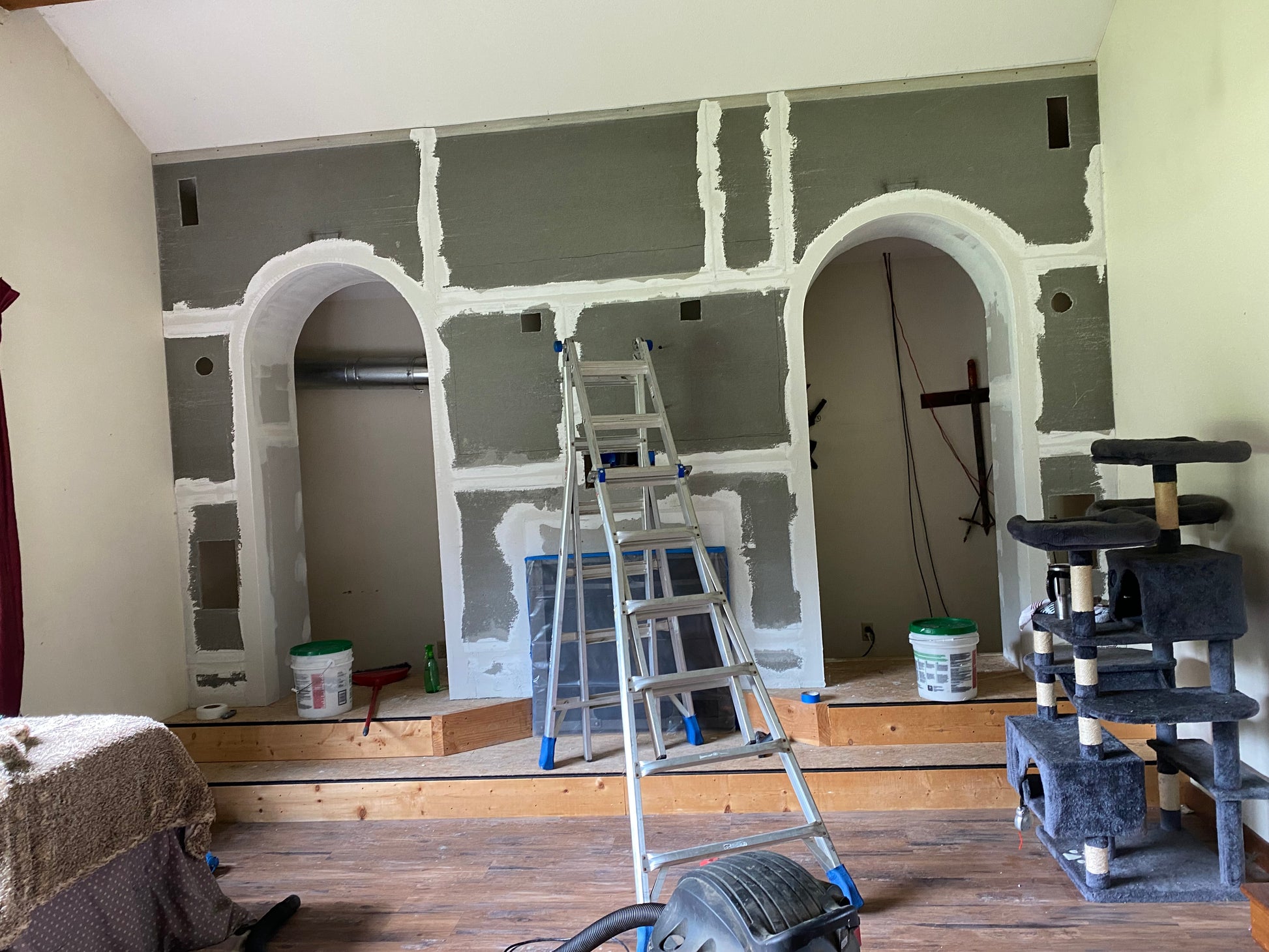 Room under construction with gray walls, arches, and a ladder.