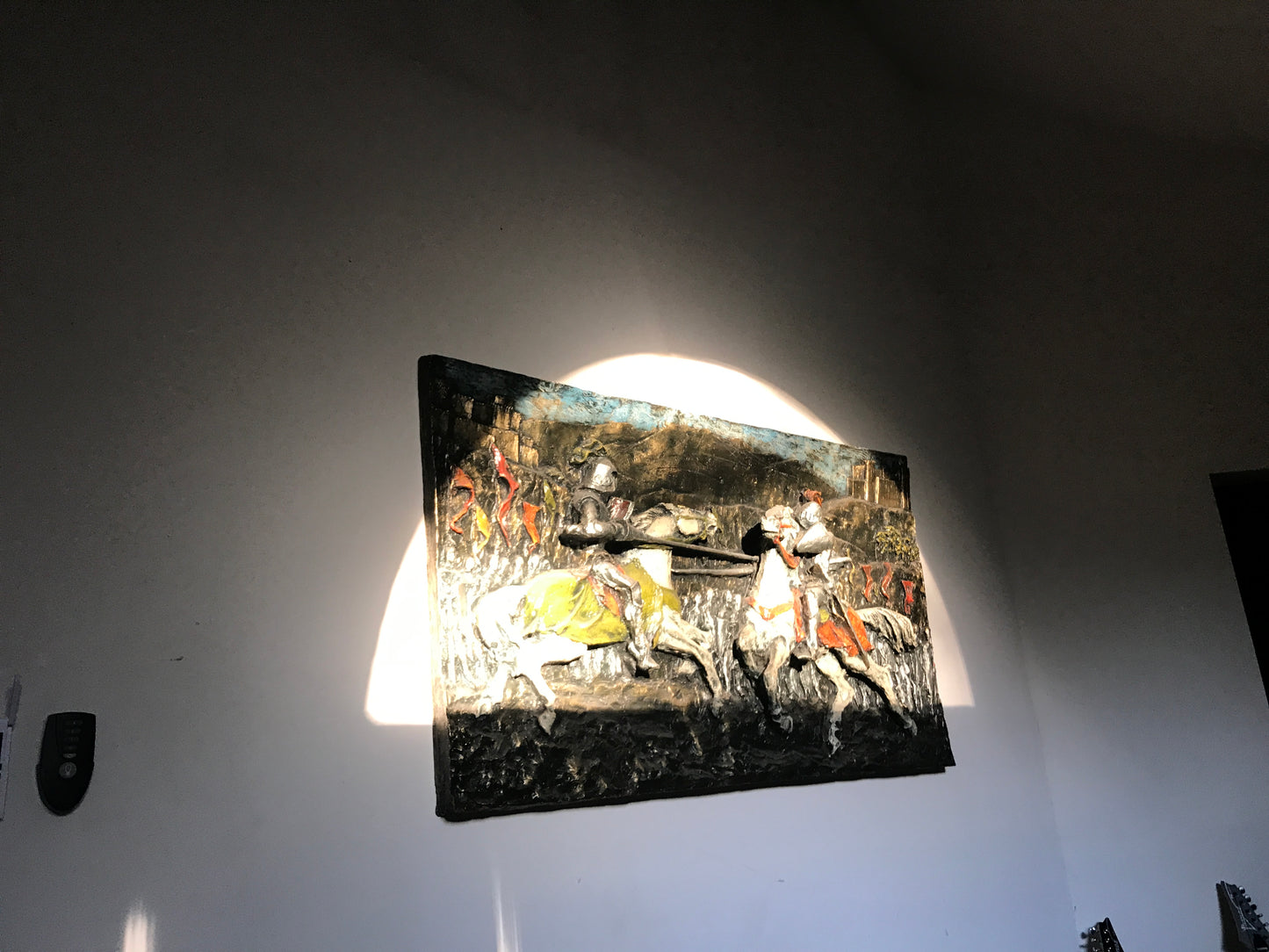 Decorative wall art with a historical scene on a plain wall.