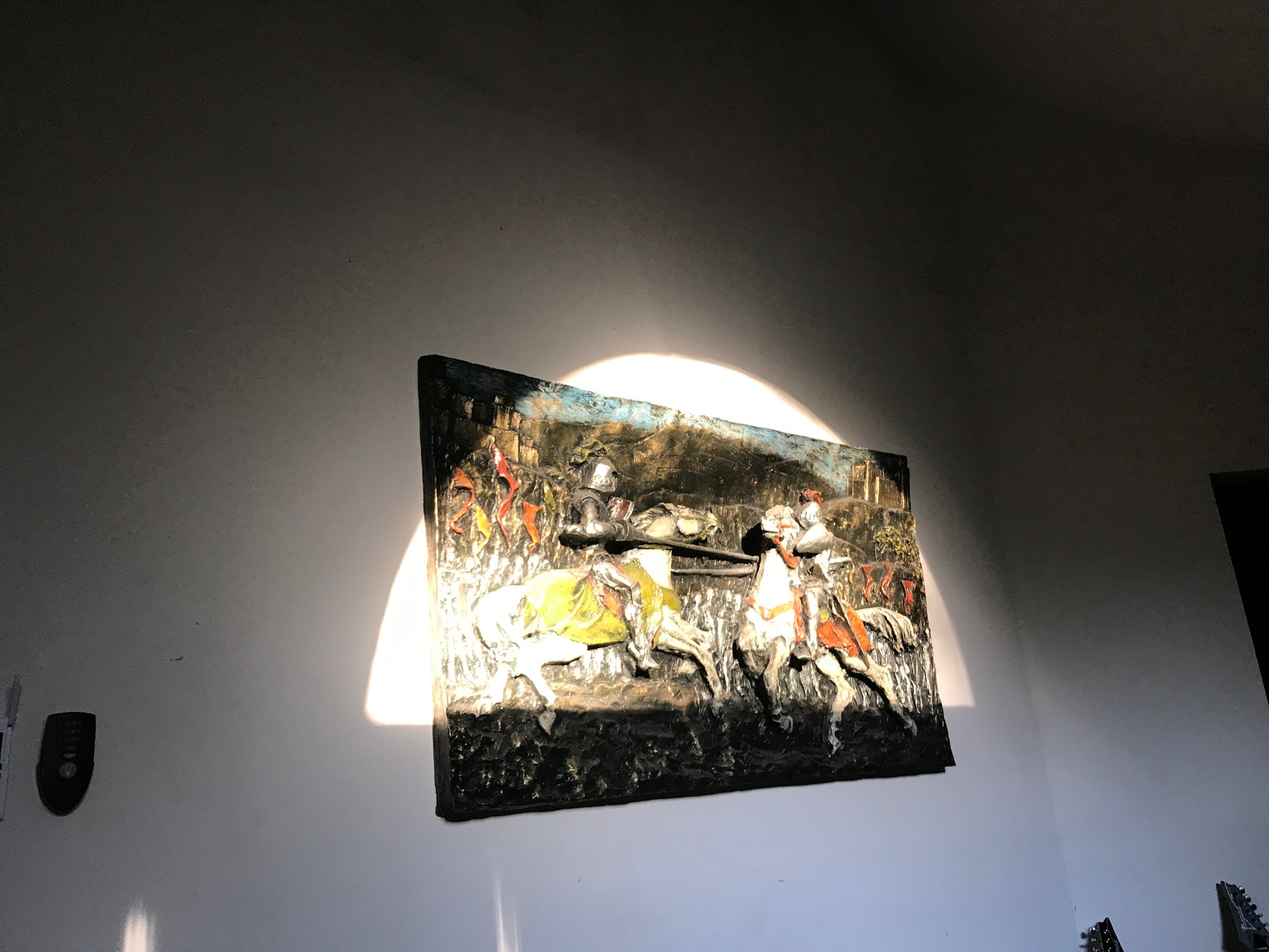 Decorative wall art with a historical scene on a plain wall.