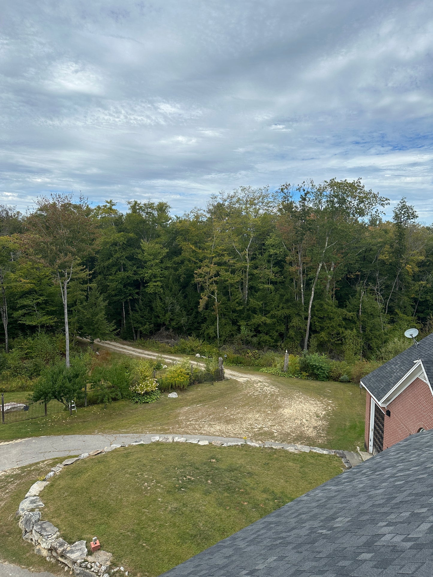 Hilly landscape with trees and a house rock walls on a cloudy day