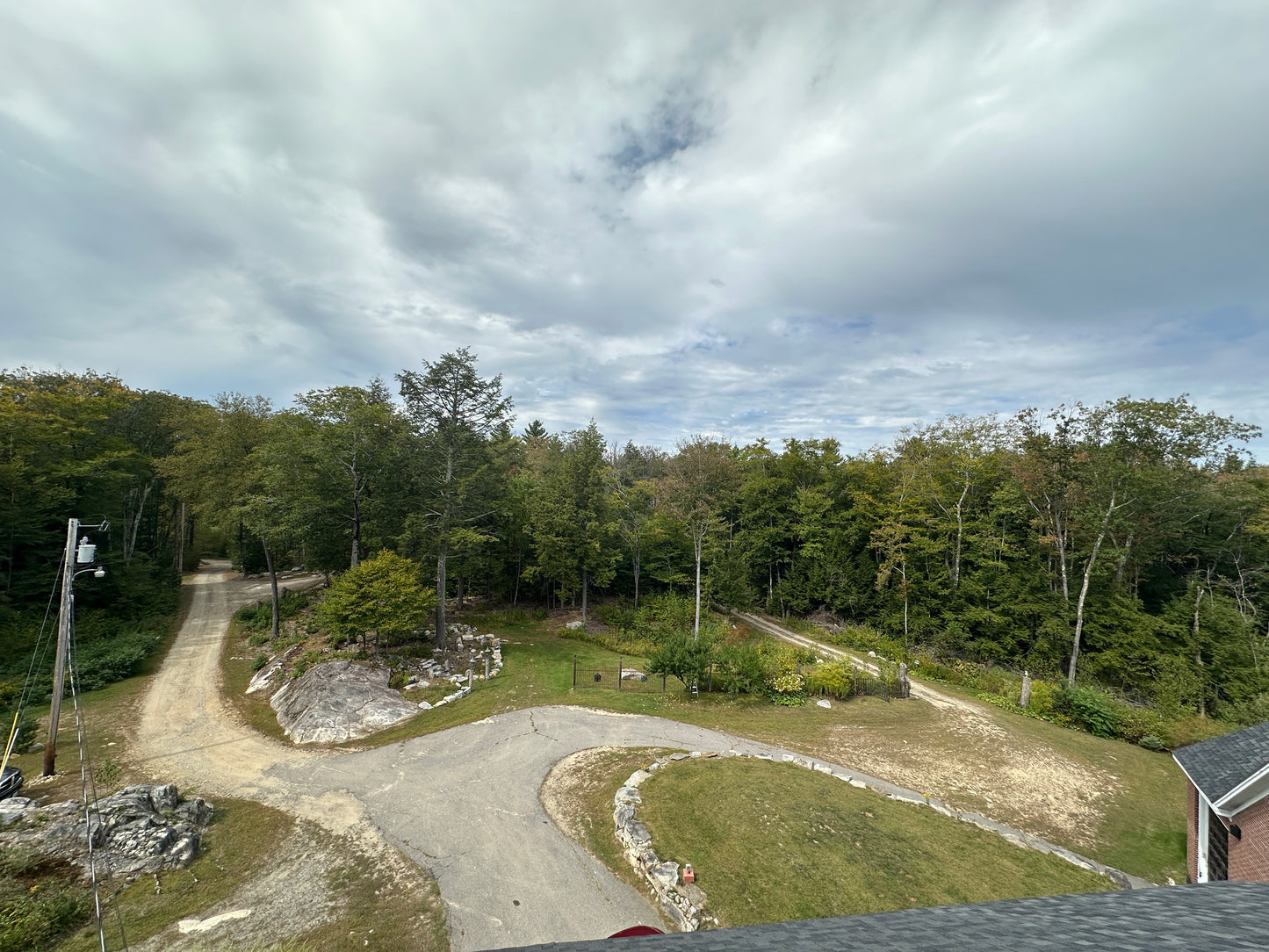 Winding dirt driveways and a circular driveway going through a forested area with a cloudy sky.