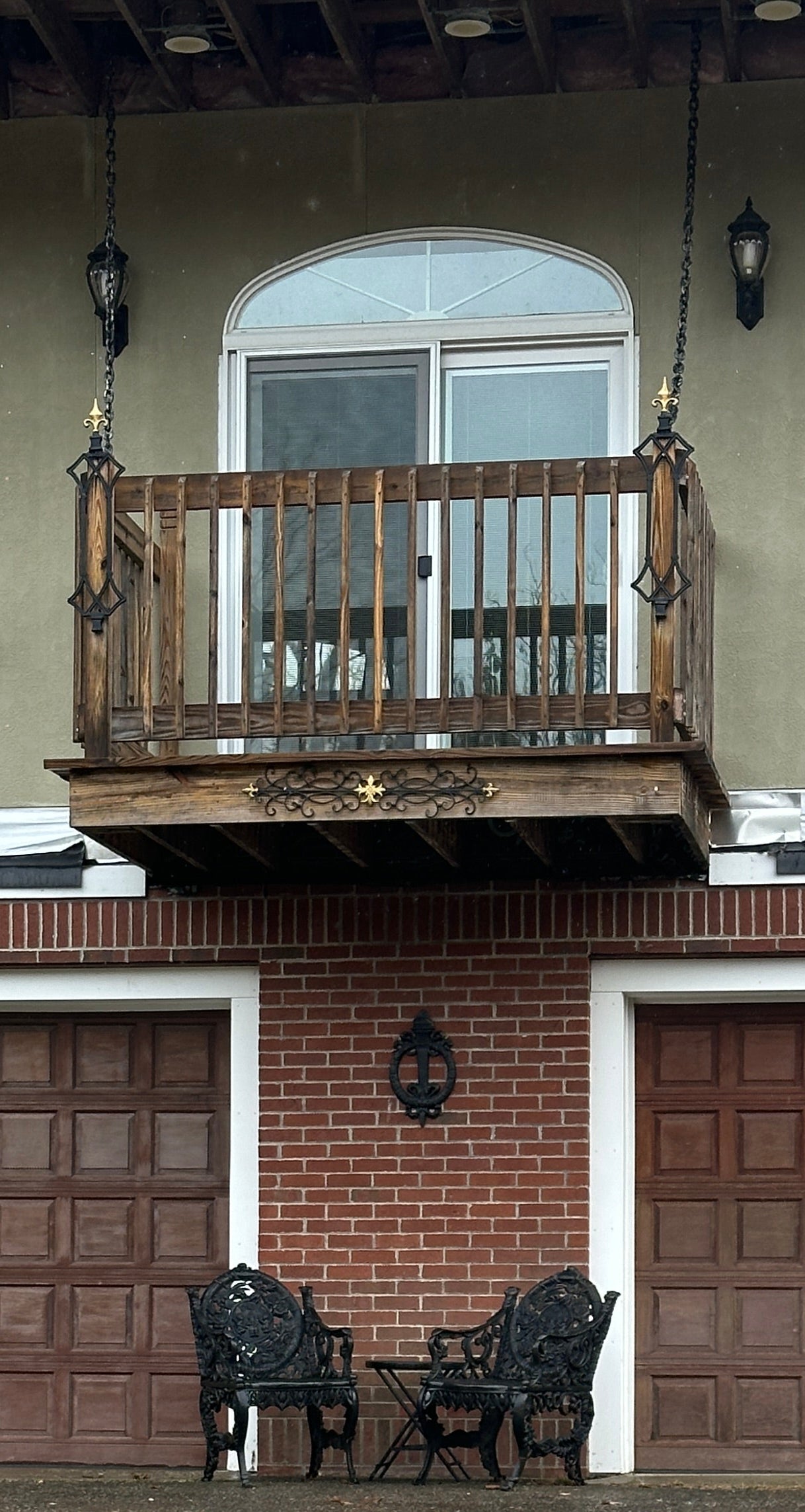 house with a brown door and balcony, viewed from a low angle.