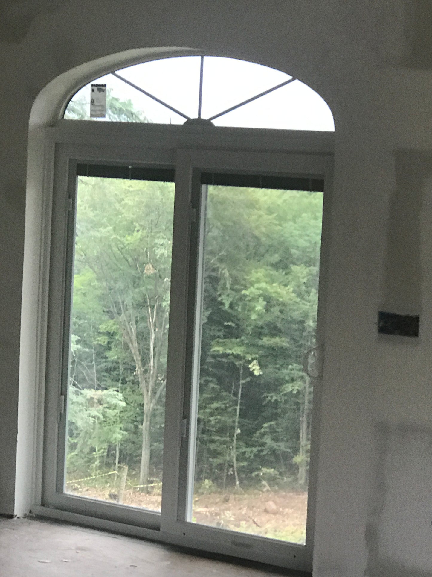 Window with a view of trees and sky, inside a building.