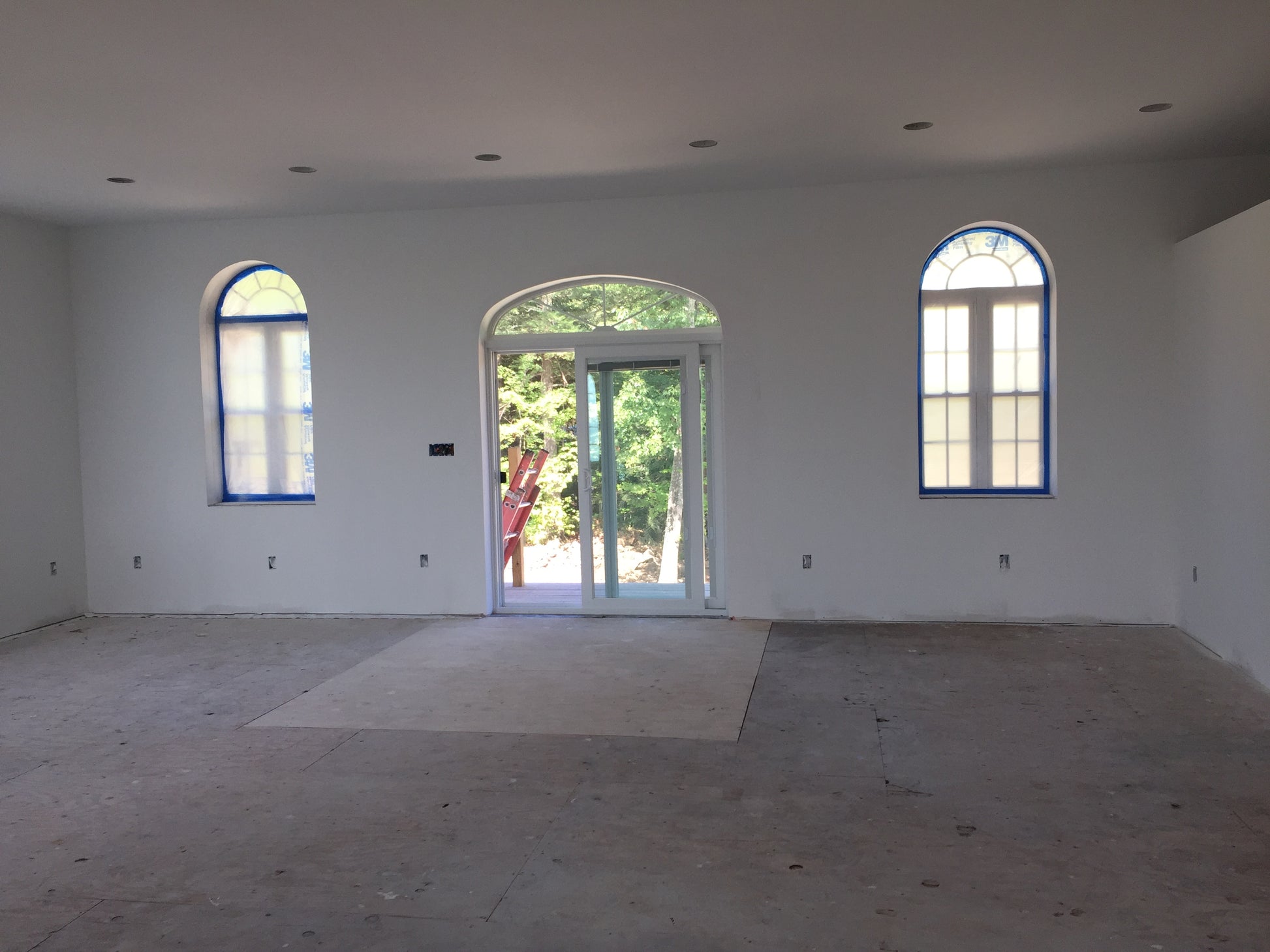 Empty room with arched windows and a door leading outside