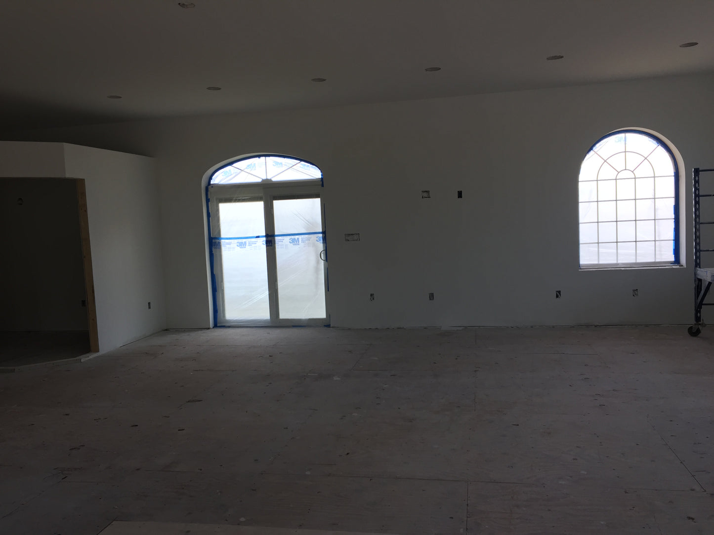 Unfinished room with large windows and bare walls