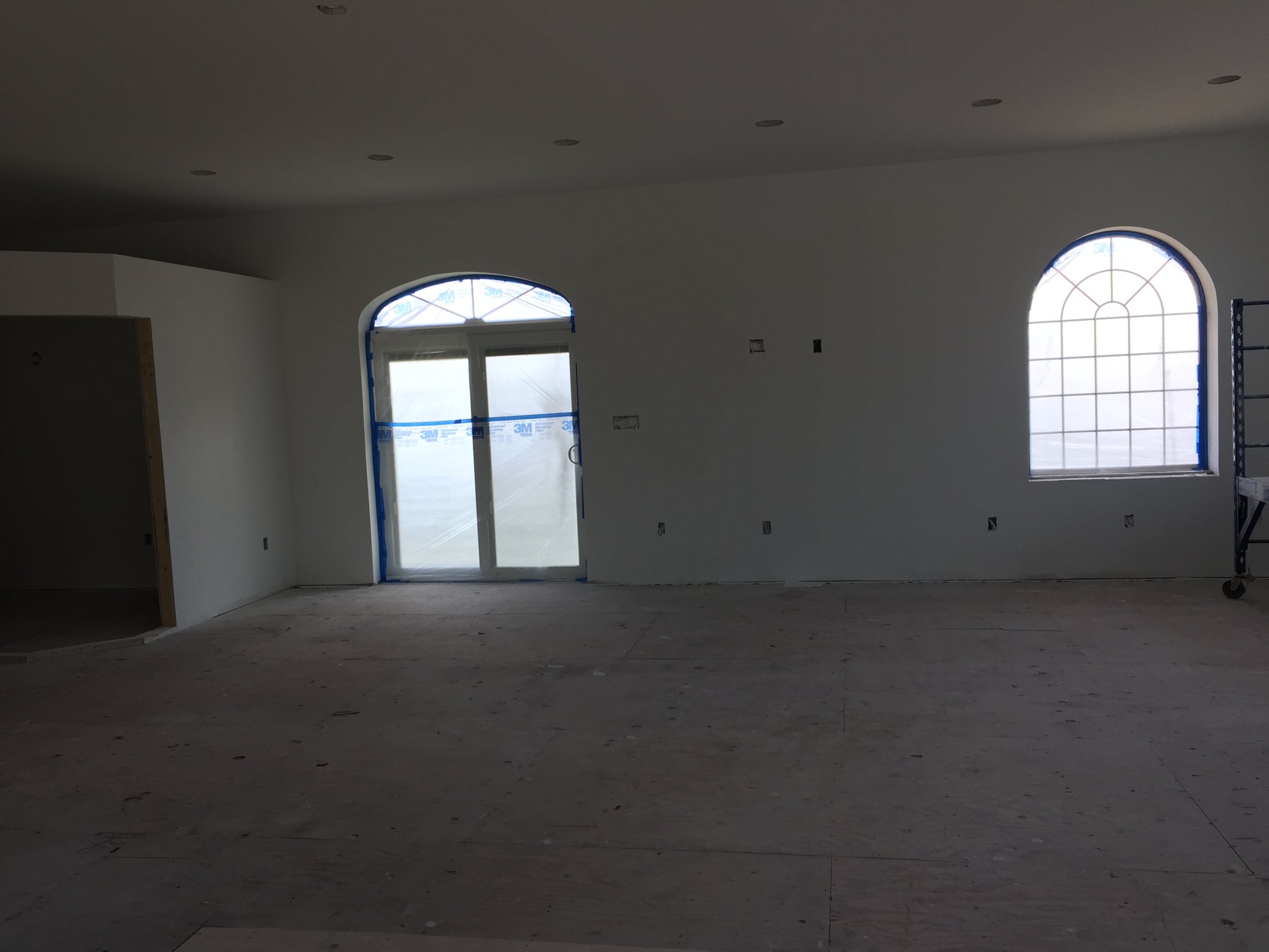 Unfinished room with large windows and bare walls