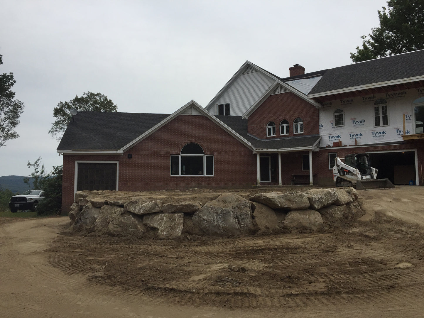 Stone wall holding front  lawn on a cloudy day. Construction of lawns.