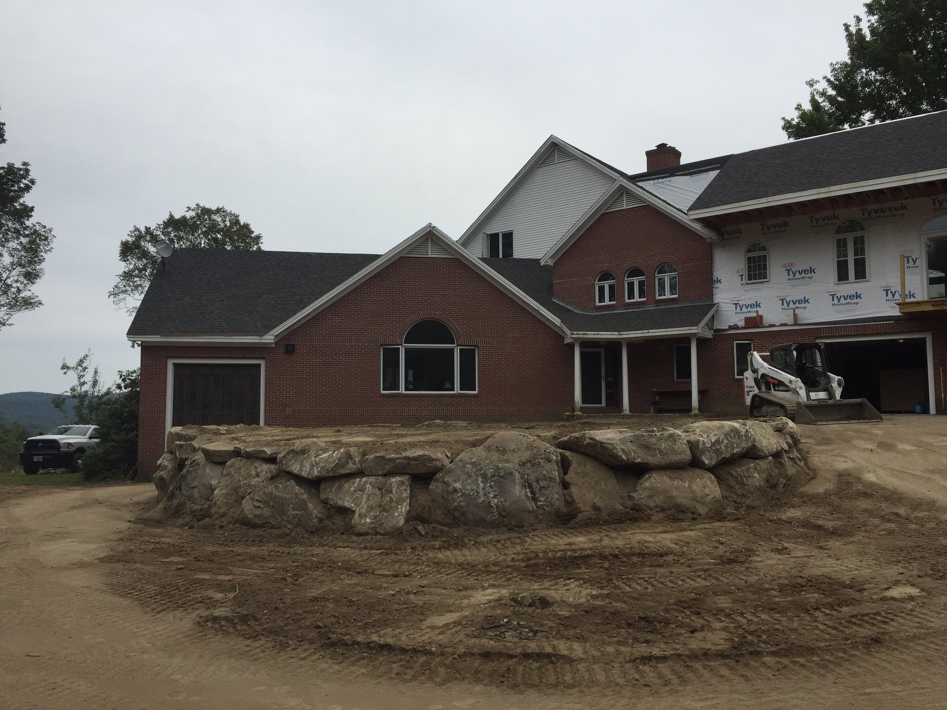 Stone wall holding front  lawn on a cloudy day. Construction of lawns.