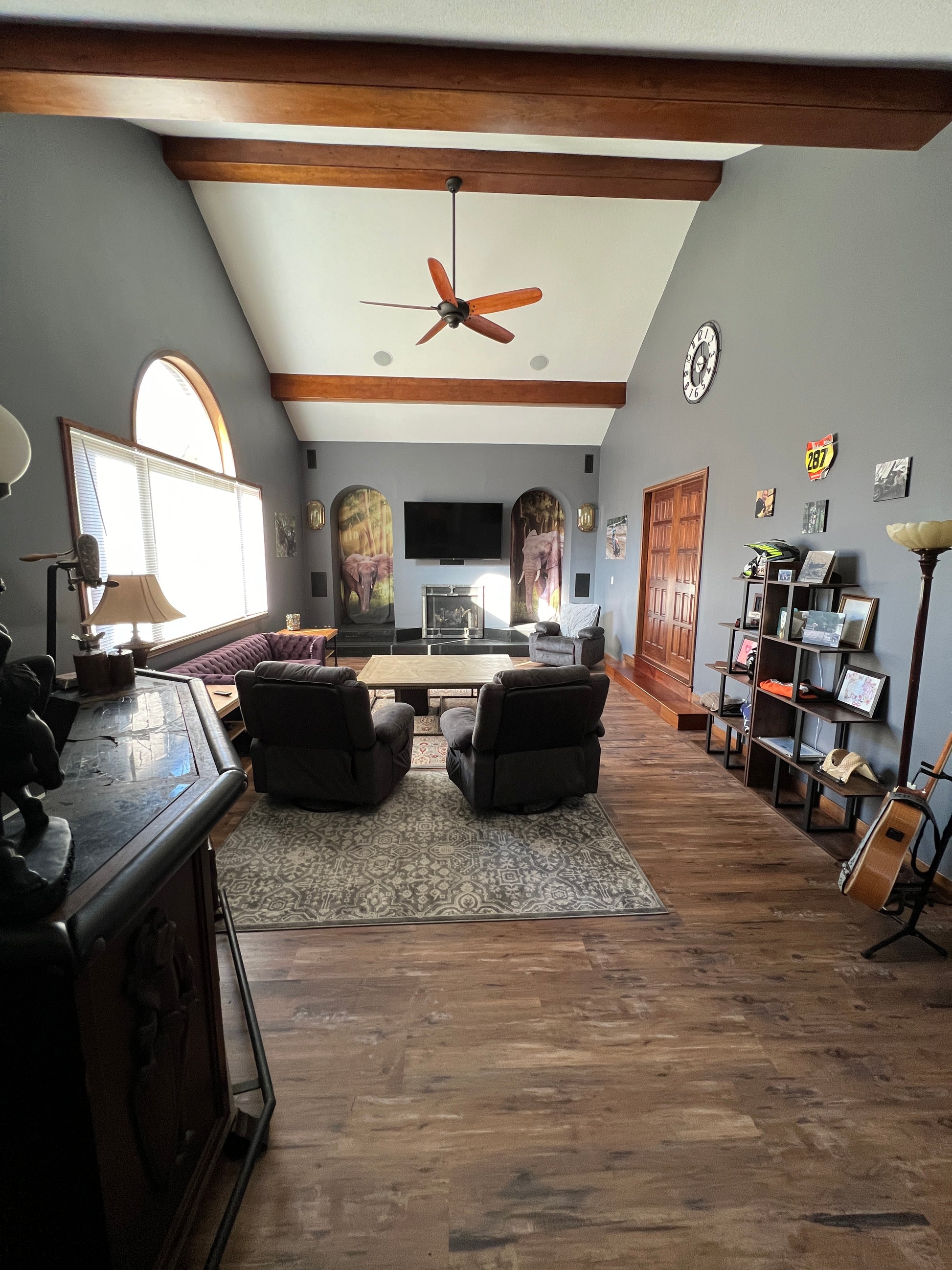 Living room with wooden floor, gray walls, and various decor items.