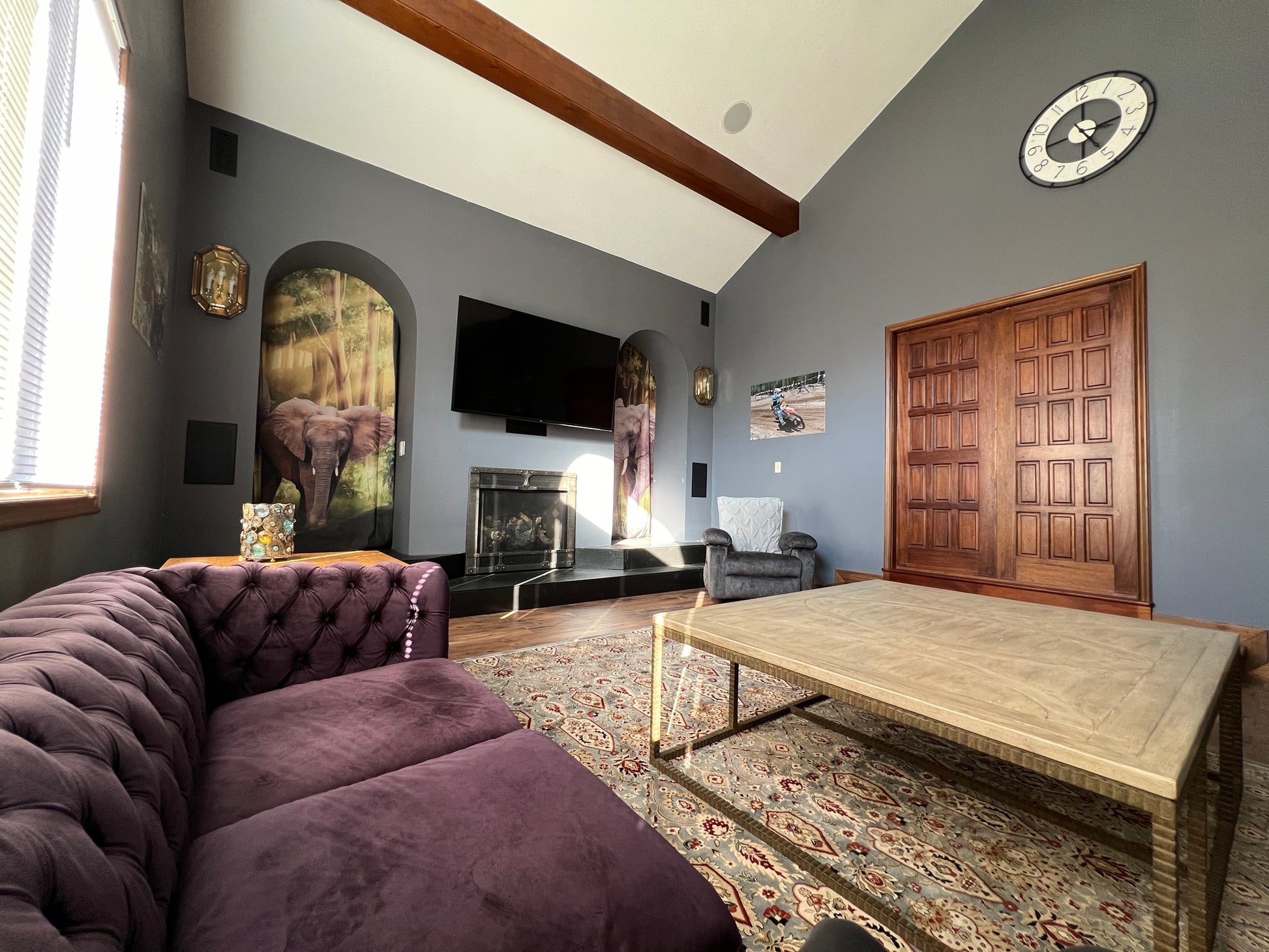 Living room with purple sofa, wooden coffee table, and decorative elements.