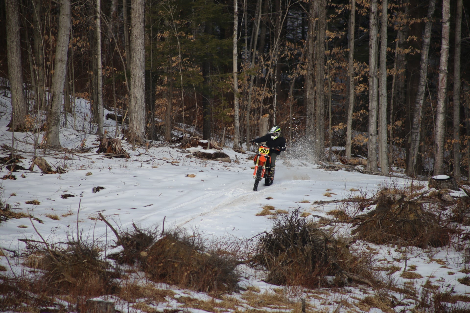 Person riding a dirt bike on a snowy motocross  trail in a forest