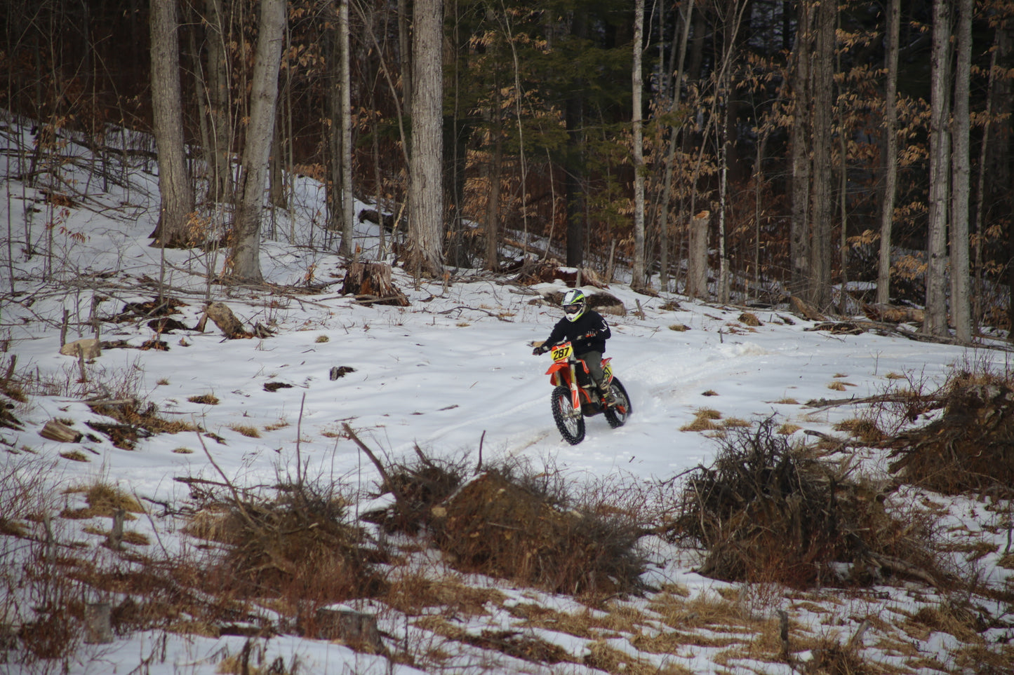 Person riding a dirt bike on a snowy  single track trail in a forest