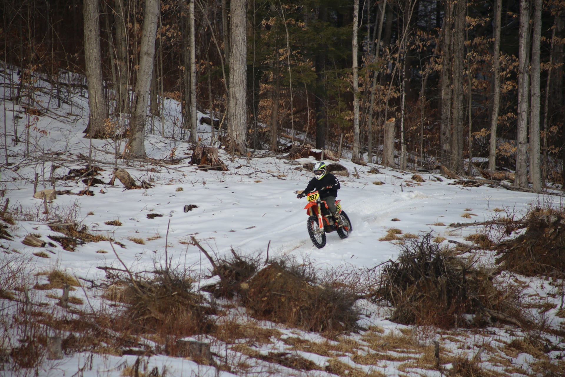 Person riding a dirt bike on a snowy  single track trail in a forest