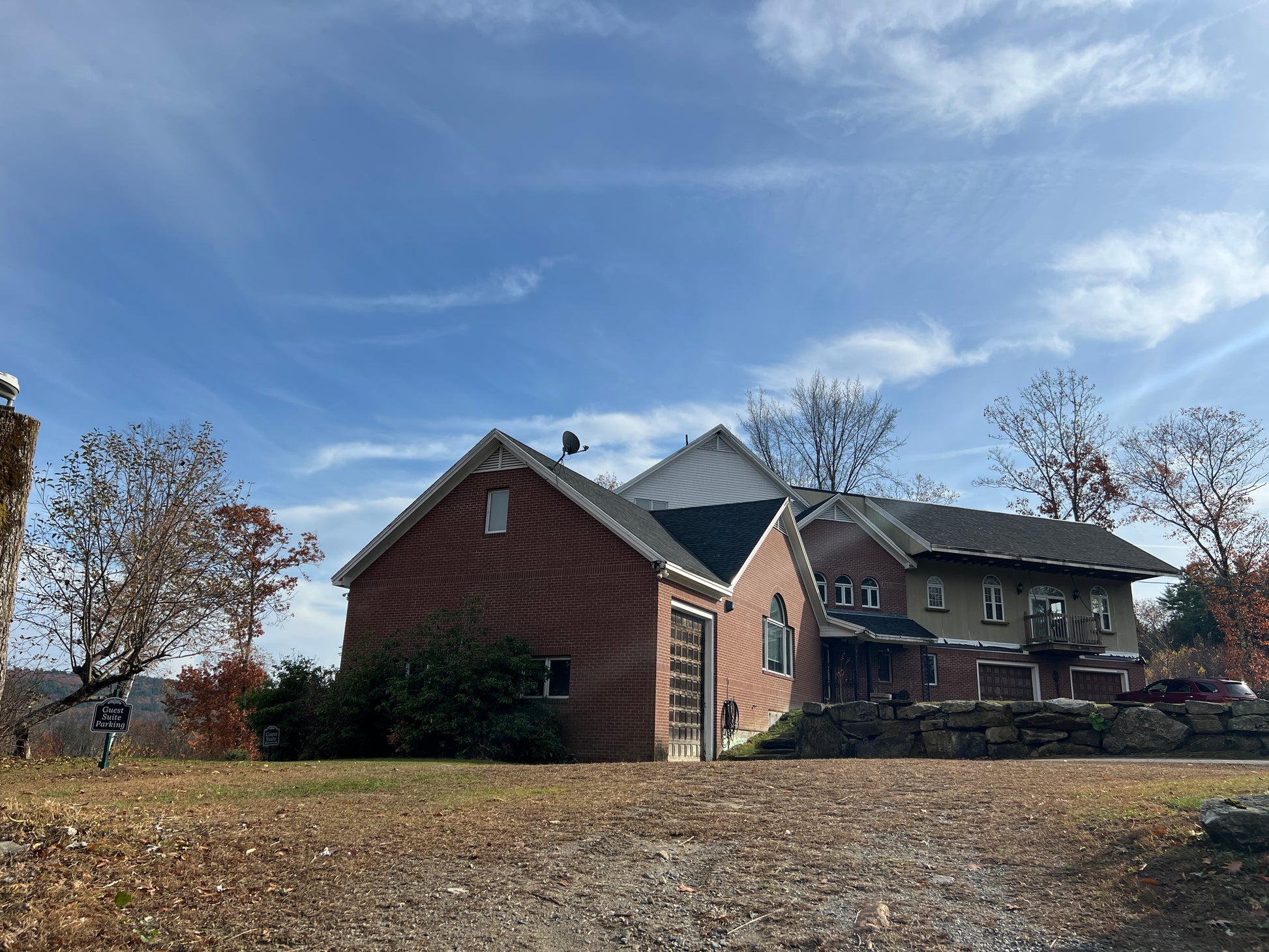 Two-story house with a brick facade and gray roof under a blue sky.