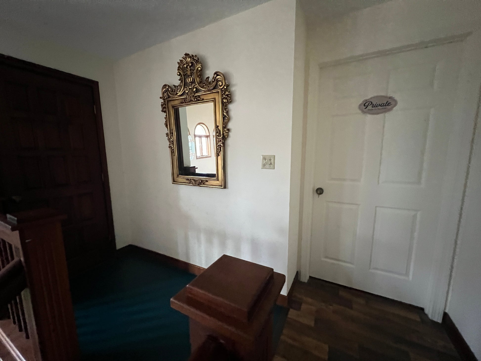 Room interior with ornate mirror on a white wall and a white door.