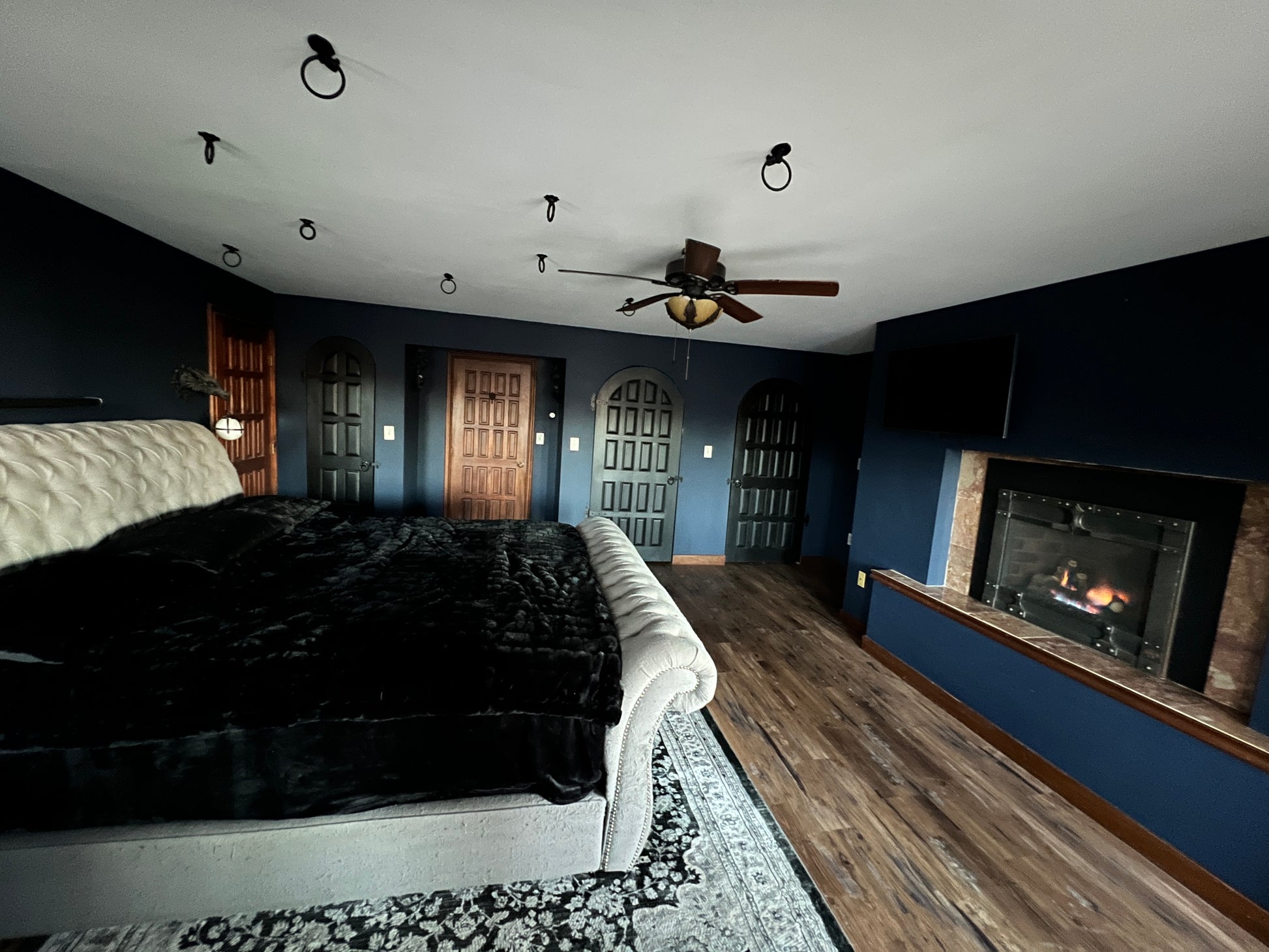 Modern bedroom with a bed, ceiling fans, and a fireplace.