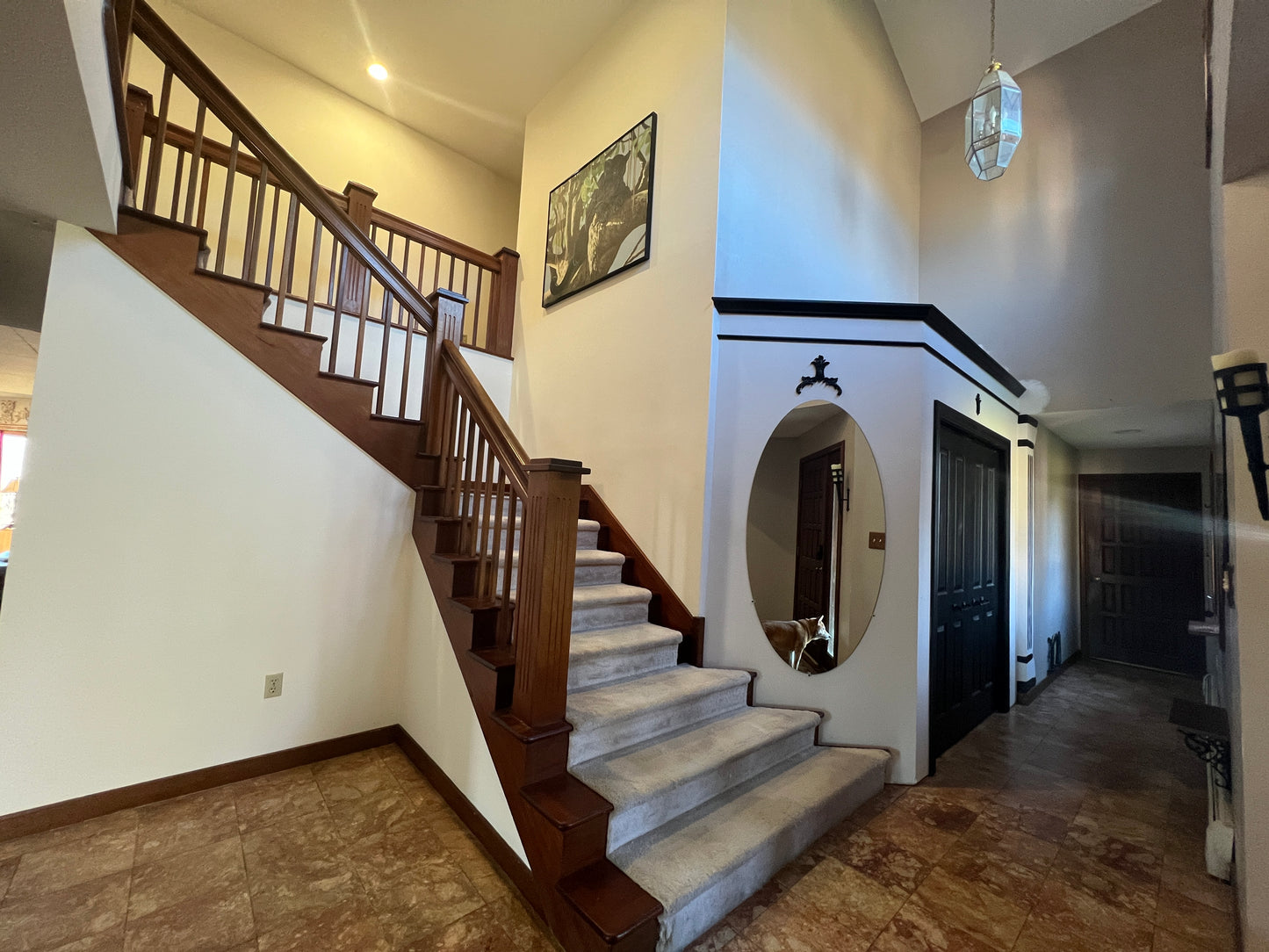 Staircase in a home with wooden mahogany railings and a mirror on the wall.