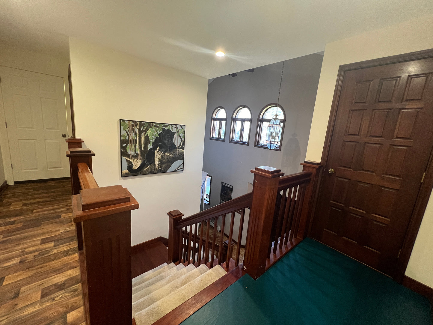 Staircase with wooden railings leading to an upper level with a painting on the wall.