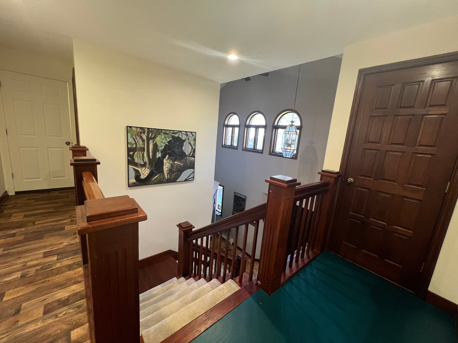Staircase with wooden railings leading to an upper level with a painting on the wall.