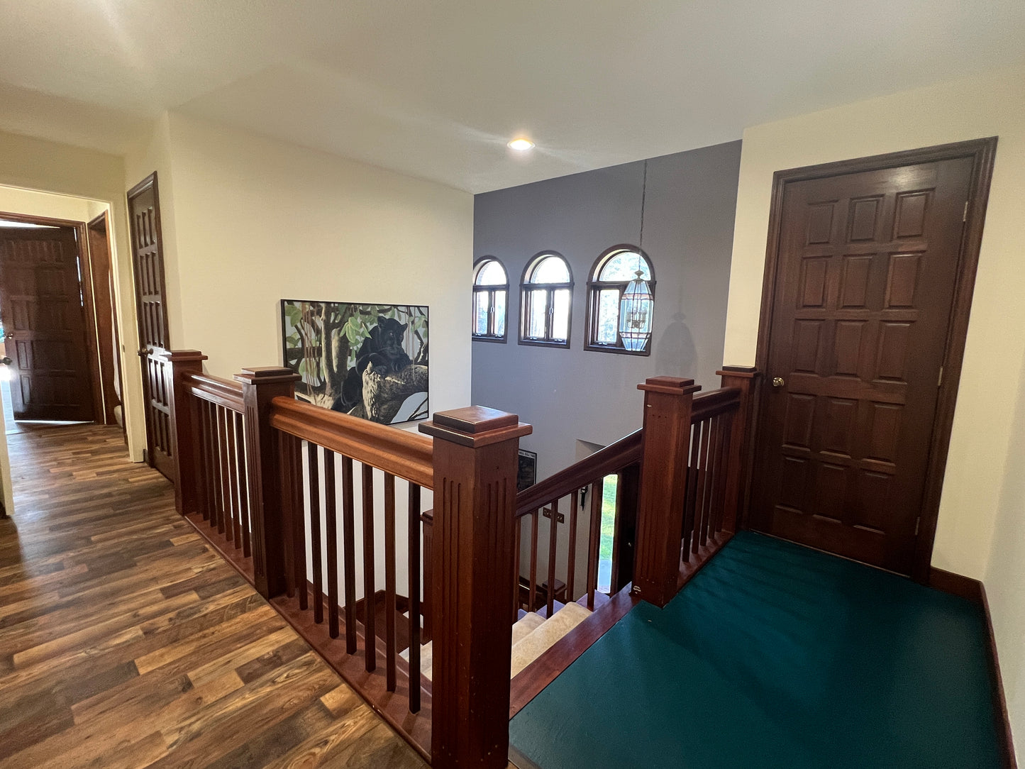 Staircase with mahogany wooden railings and a painting on the wall in a home interior.