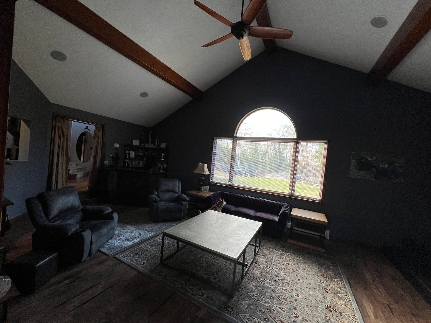 Living room with dark walls, wooden beams, and a large window.