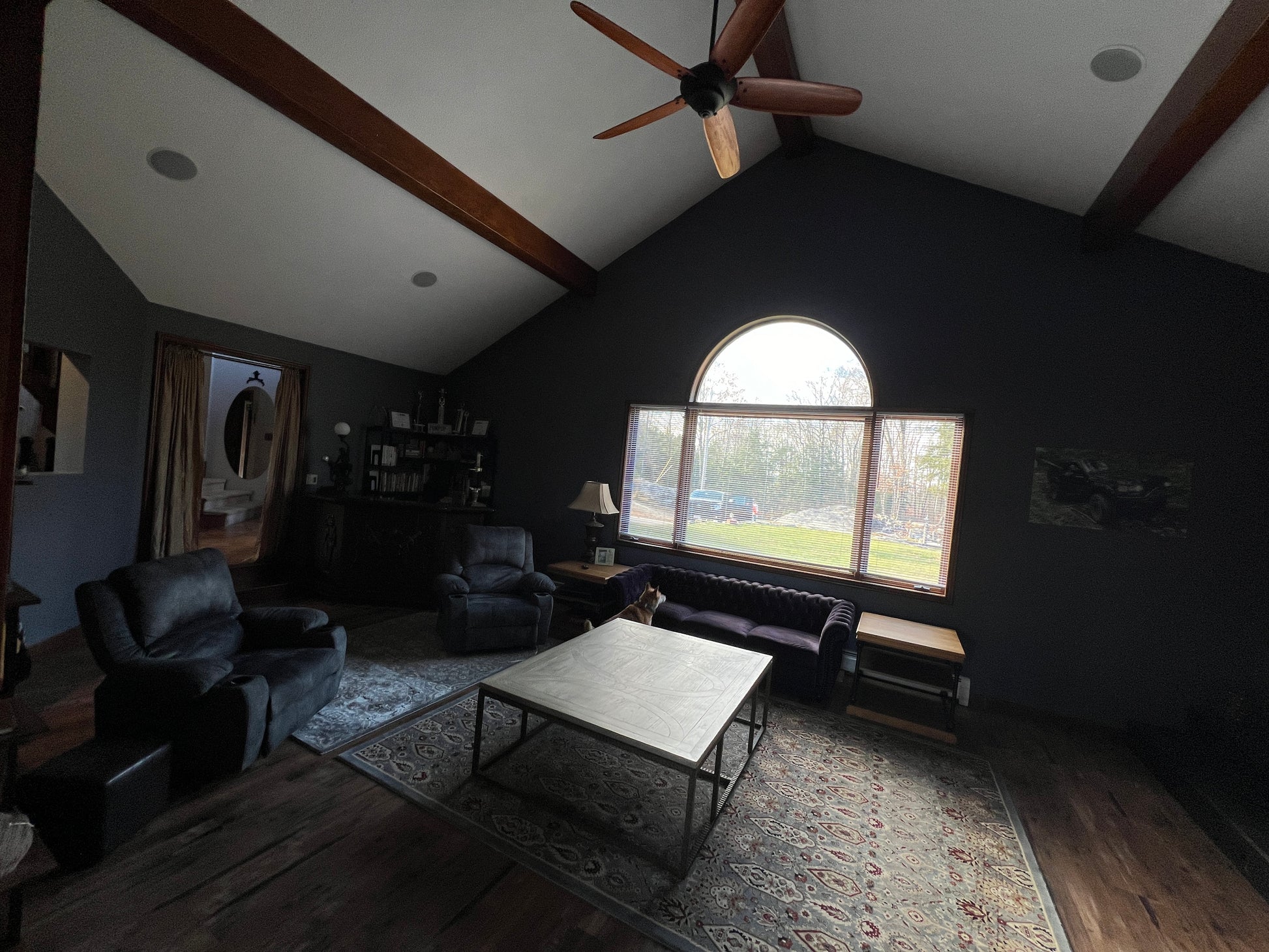 Living room with dark walls, wooden beams, and a large window.