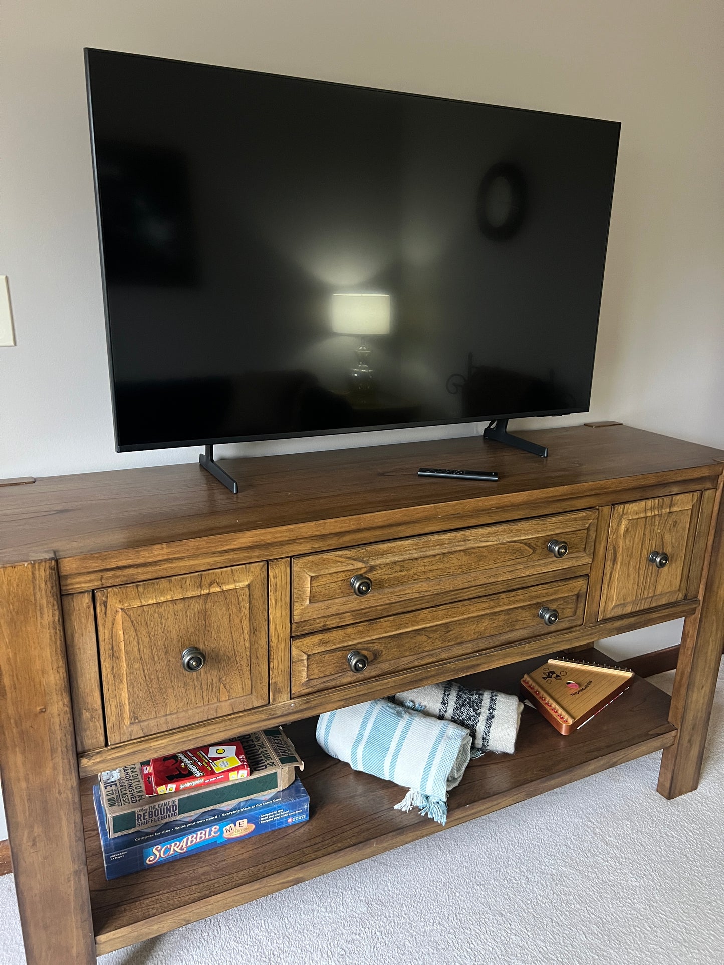 Wooden entertainment console with a television on a white wall